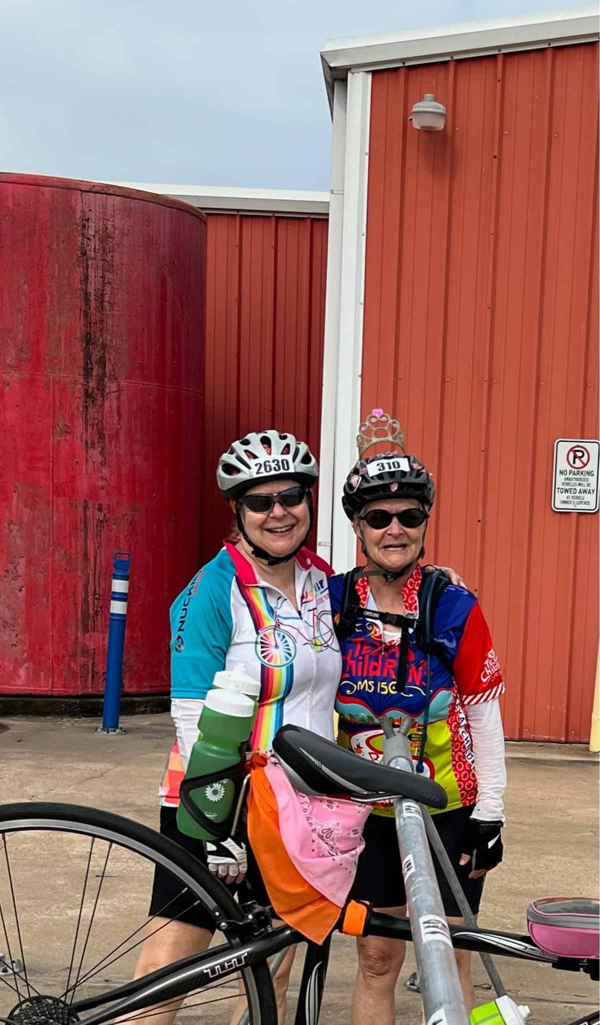 Smiling women cyclists in colorful jerseys with helmets at Bluebonnet Express location.
