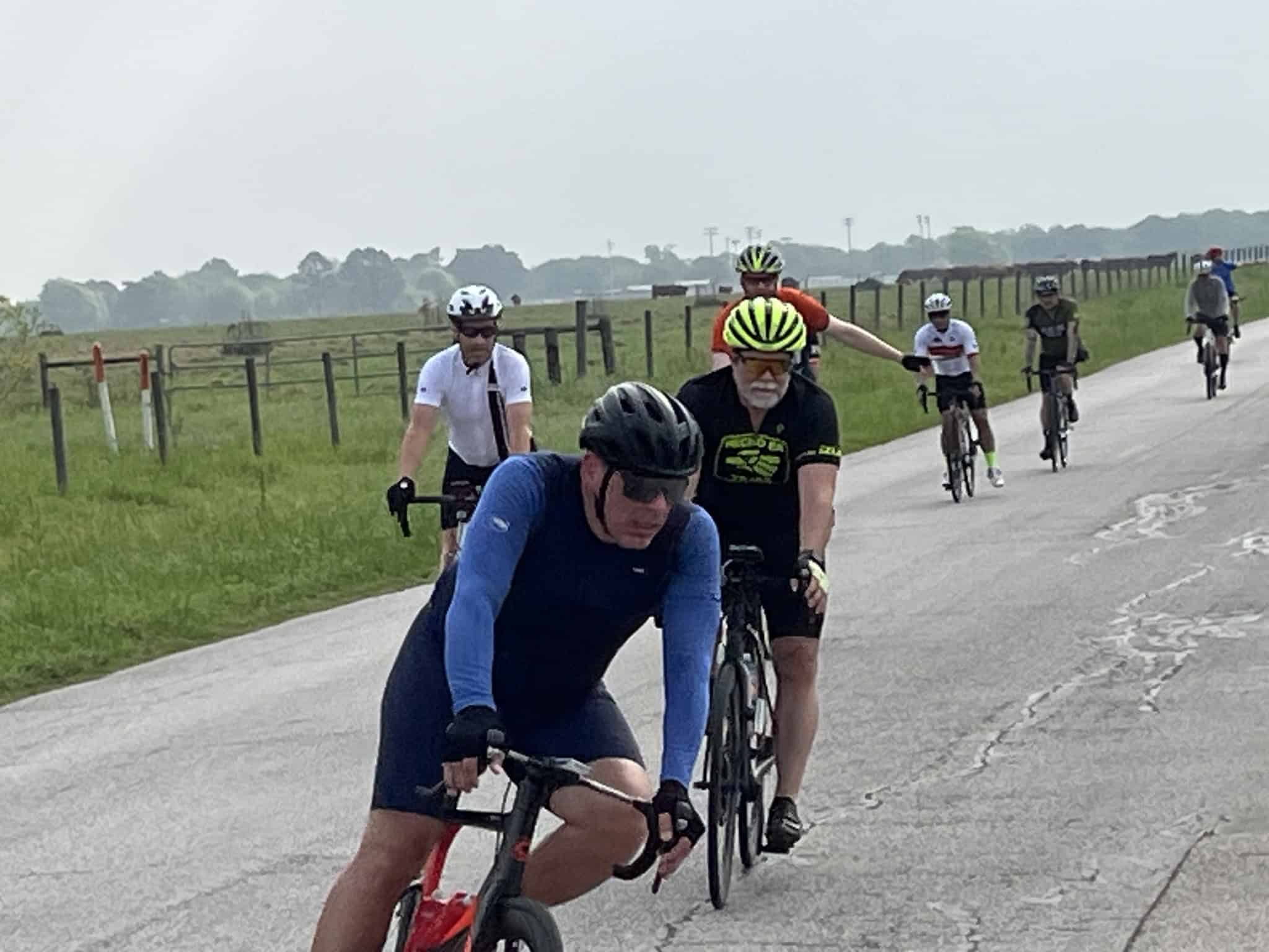 Biking group riding on a rural road, enjoying scenic views on Bluebonnet Express cycling route.
