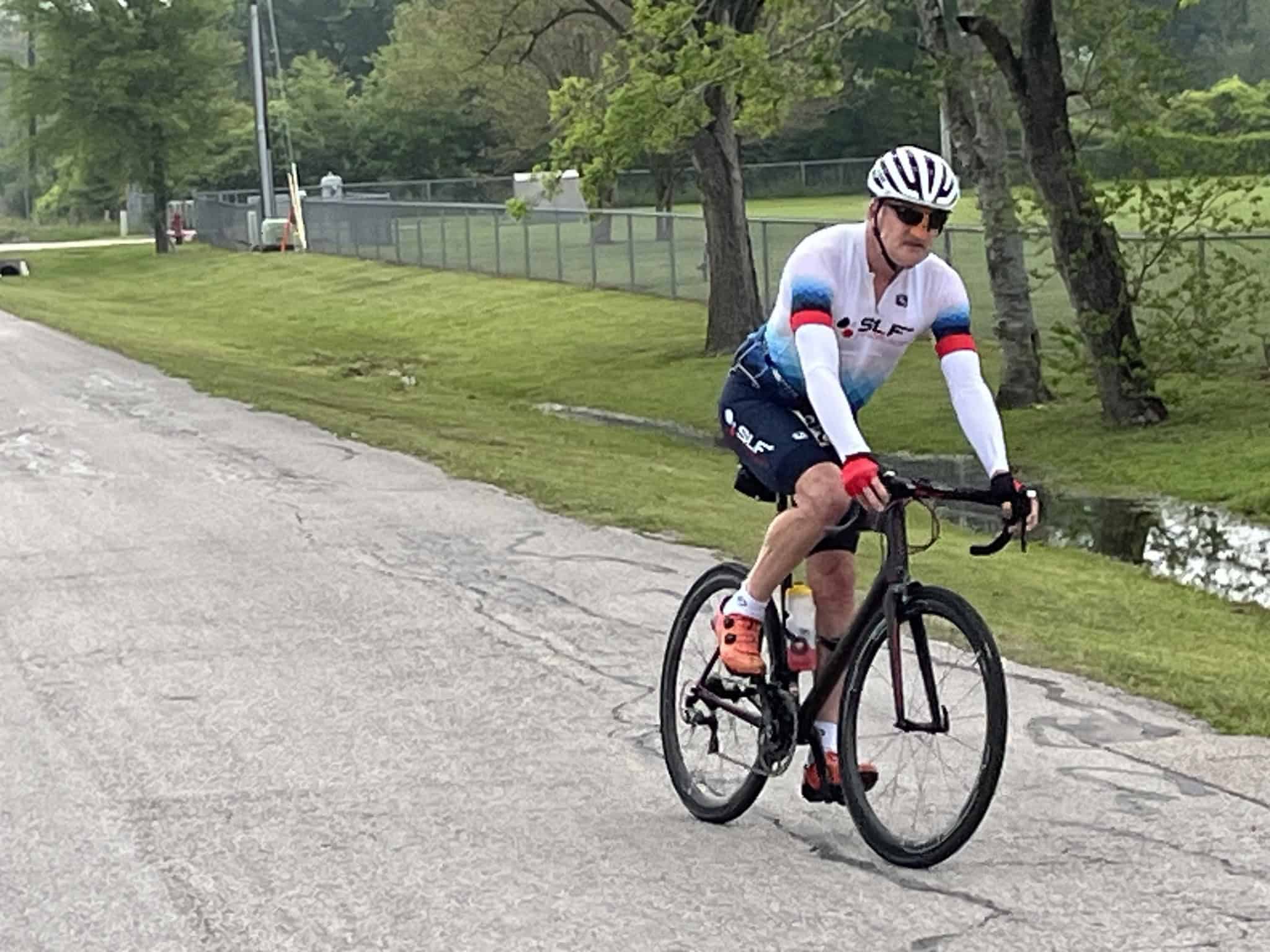 High-performance cyclist riding on a paved trail, promoting Bluebonnet Express biking events.