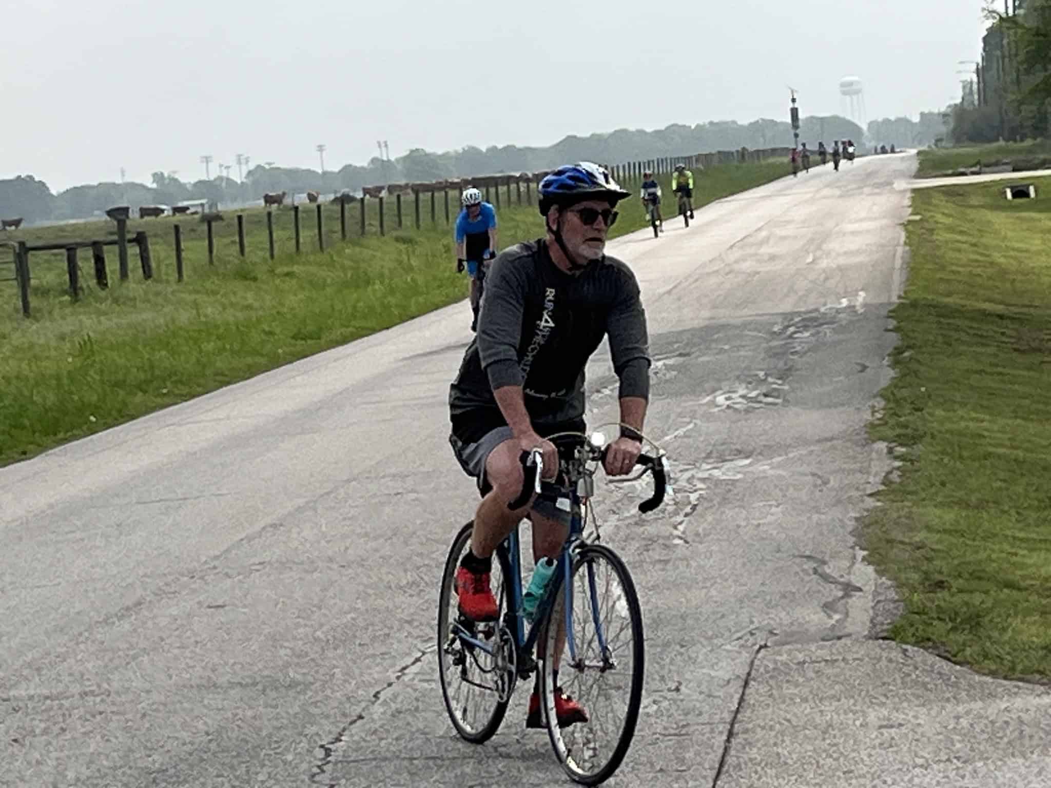 Bright blue bicycle with a cyclist on a scenic rural trail during daytime.