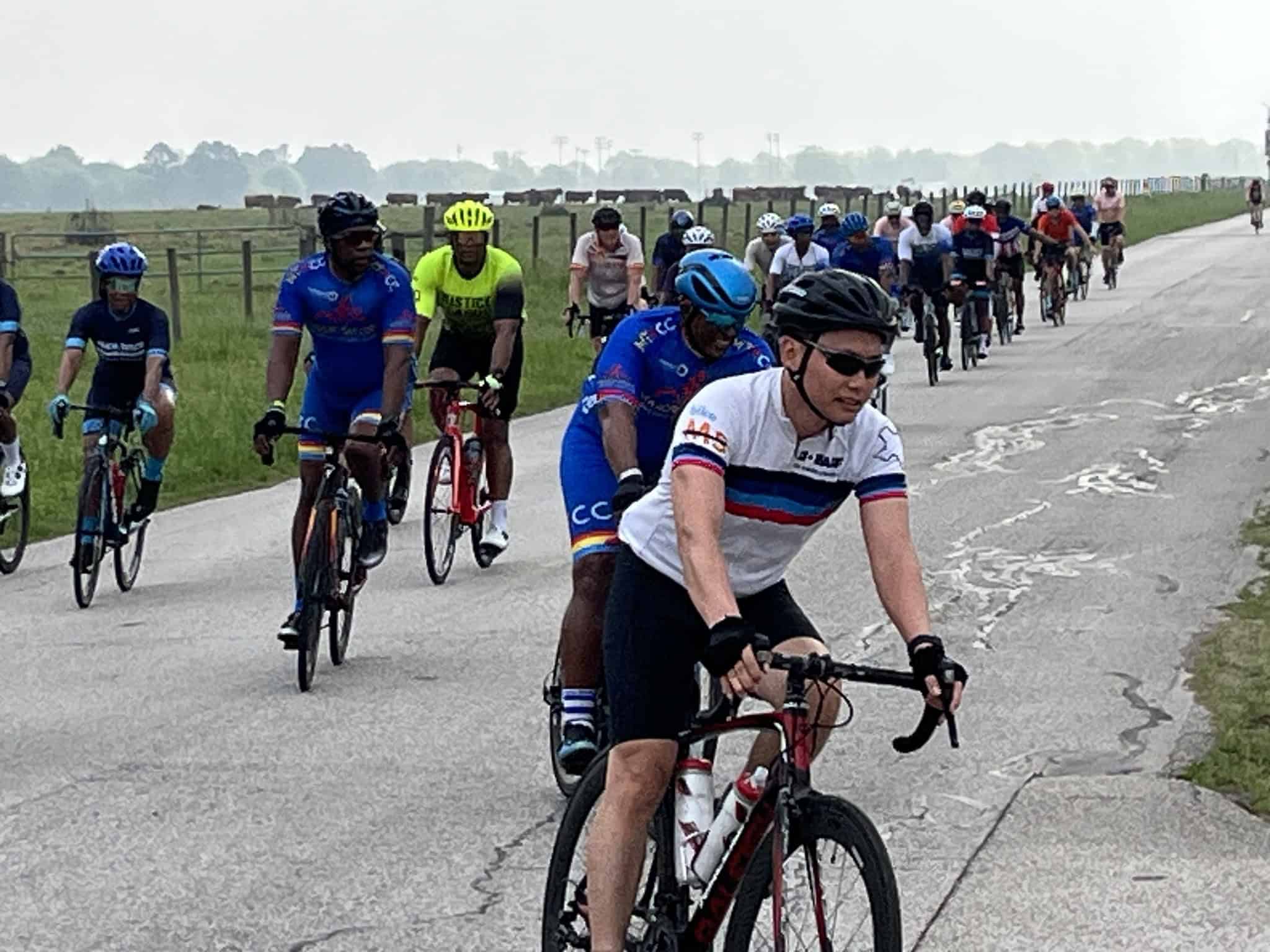 Vibrant group of cyclists riding on scenic countryside road during Bluebonnet Express event.