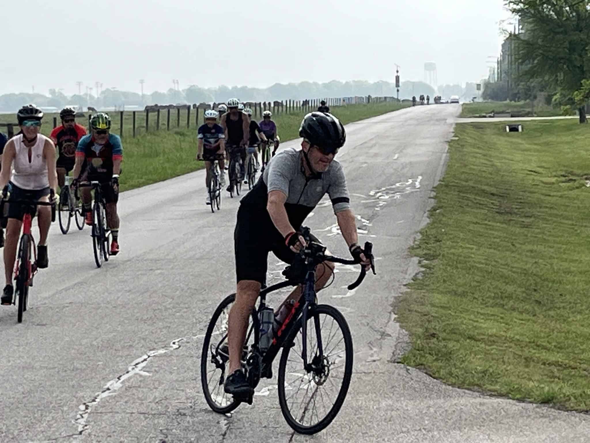 Vibrant group of cyclists rides along scenic rural road, enjoying outdoor bike tour, fitness, and nature. Perfect for cycling enthusiasts and outdoor adventure.