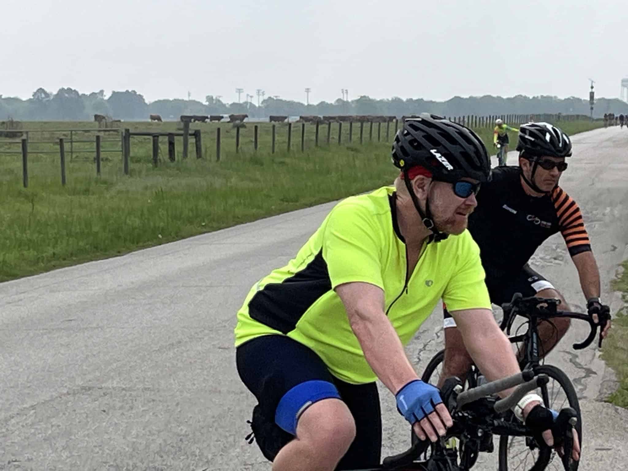 Vibrant cyclist wearing yellow jersey riding along scenic countryside bike trail.