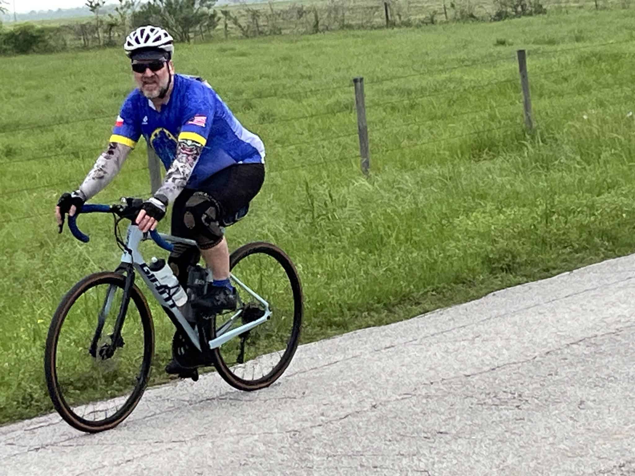 Vibrant cyclist riding a blue bike on scenic countryside trail, promoting outdoor adventures.