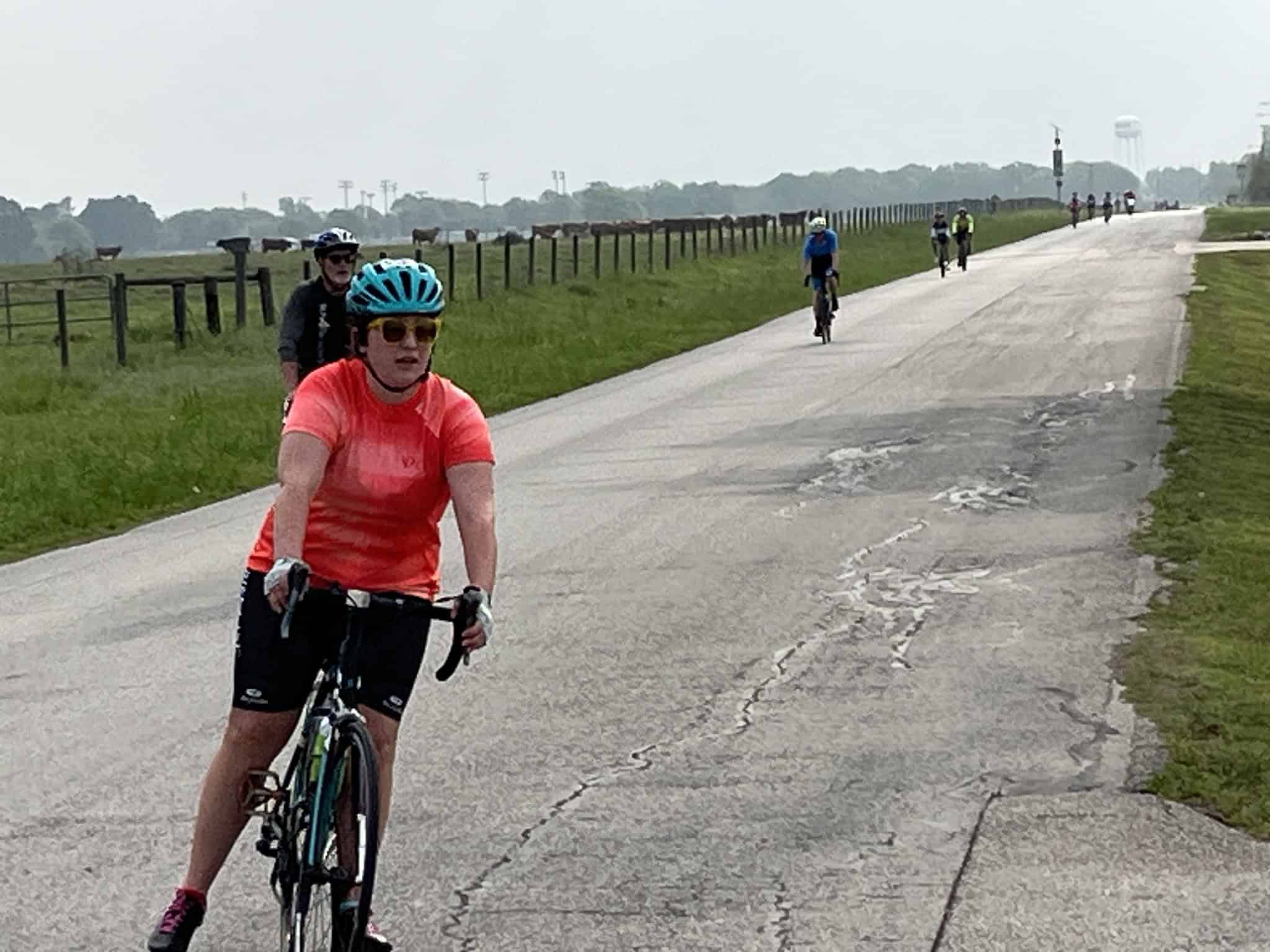 Bright woman riding a bicycle on a rural road during daytime, Healthy lifestyle, Outdoor cycling, Bluebonnet Express route.