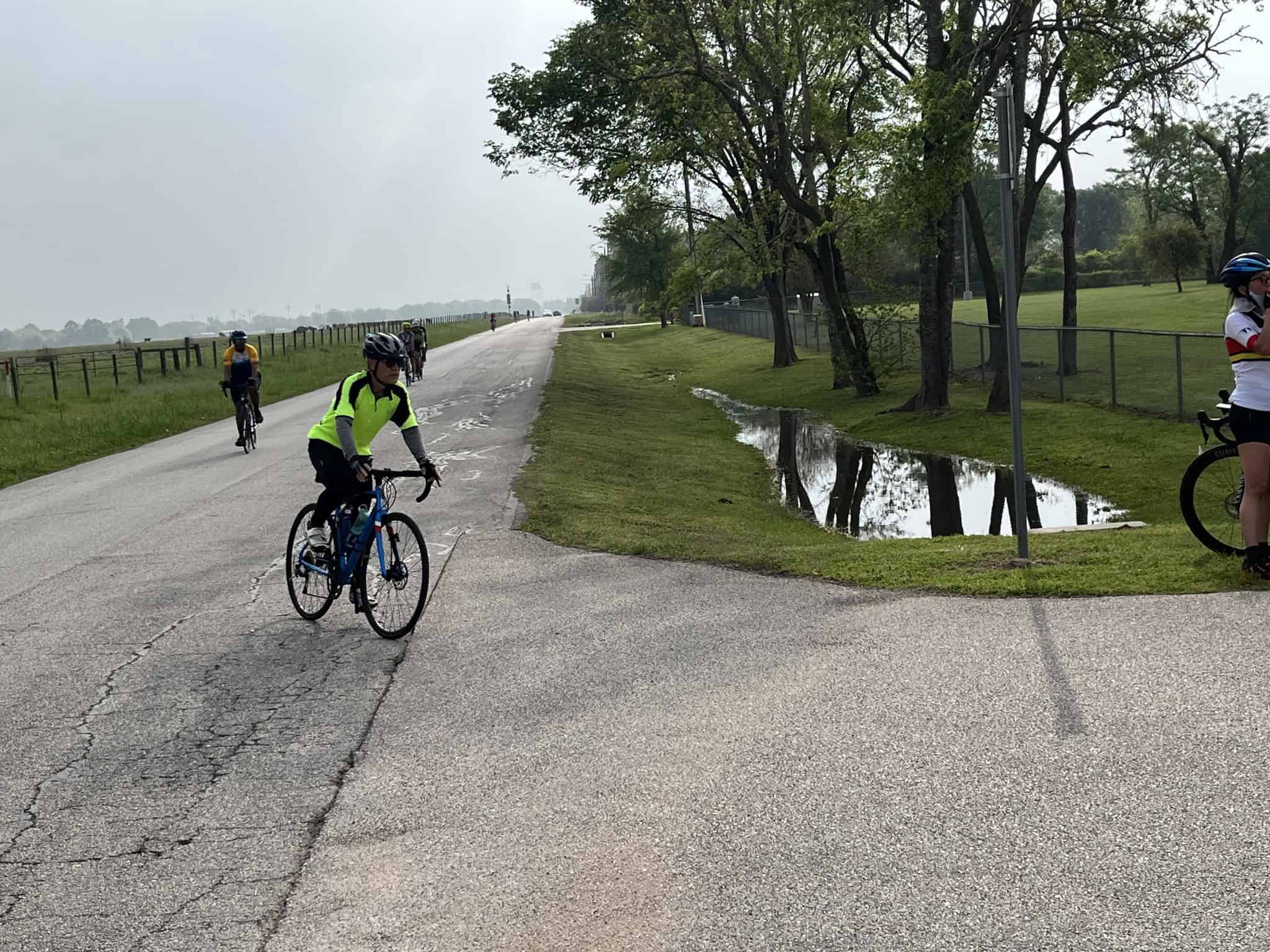 Bright yellow and black cycling jersey on a rider on a paved path in a scenic park setting.