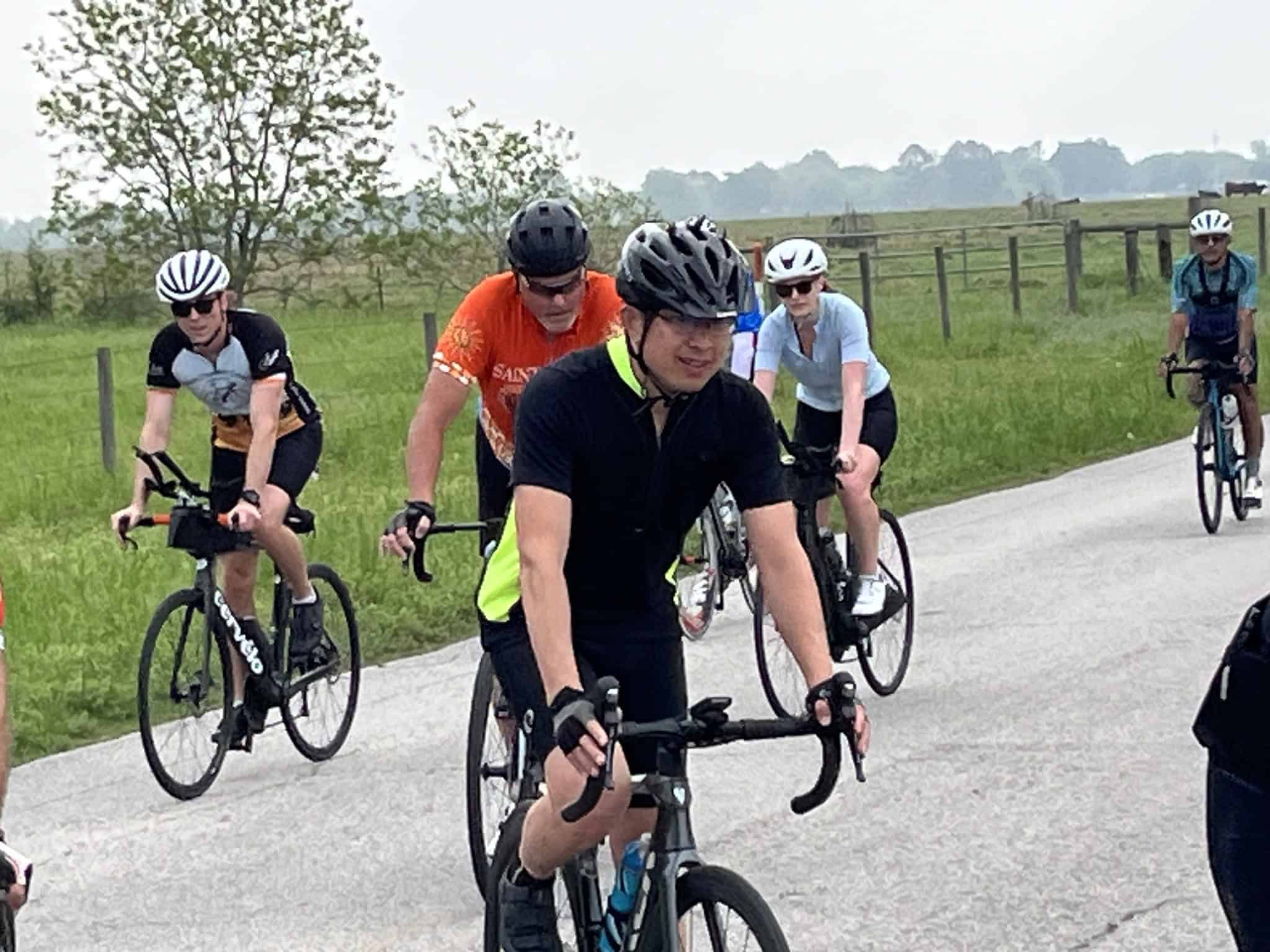 Cyclists riding on scenic countryside road, celebrating Bluebonnet Express event, enjoying outdoor biking adventure.