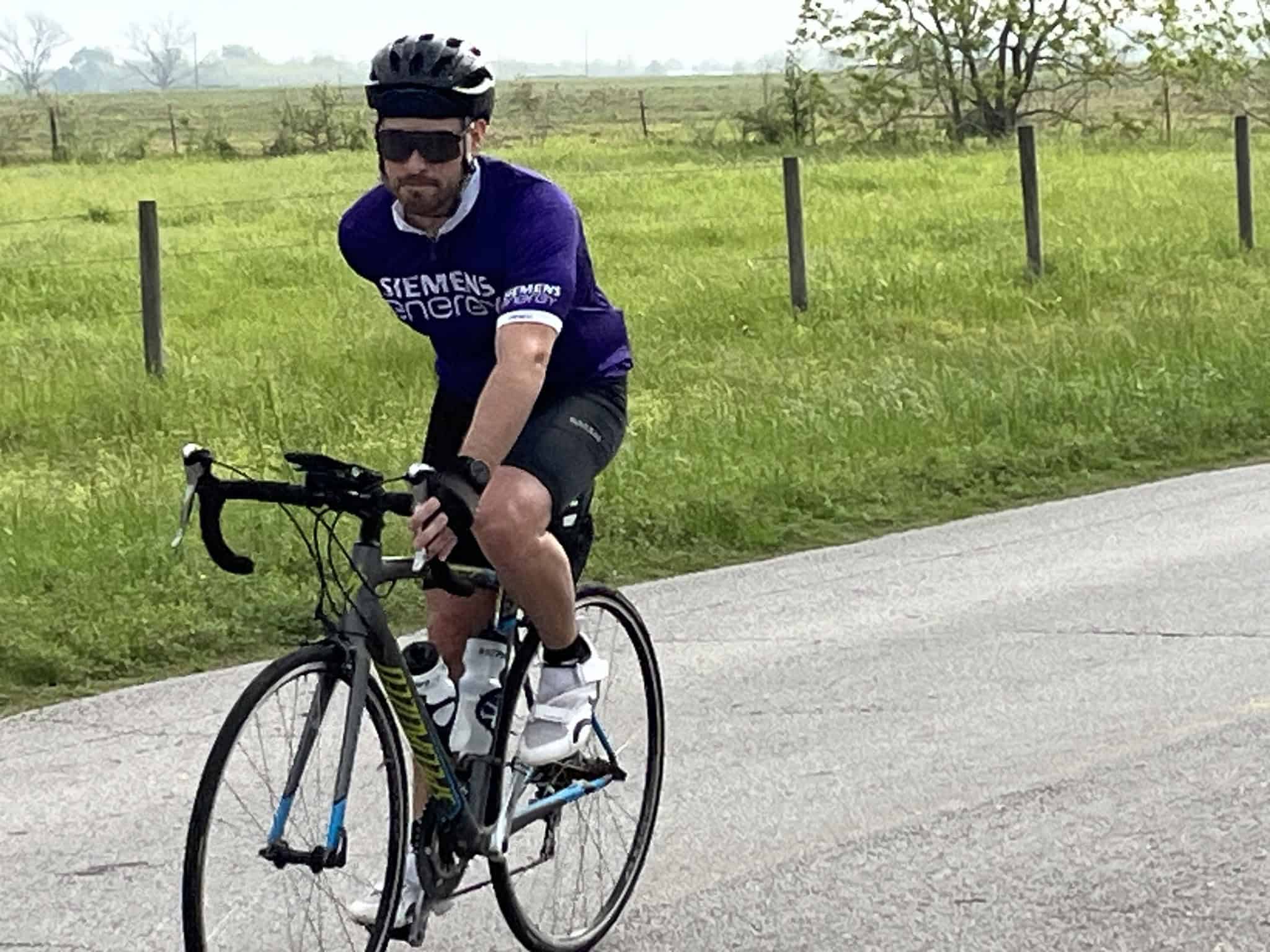 Man cycling on scenic rural road in Green Texas with Bluebonnets, supporting Bluebonnet Express biking event.