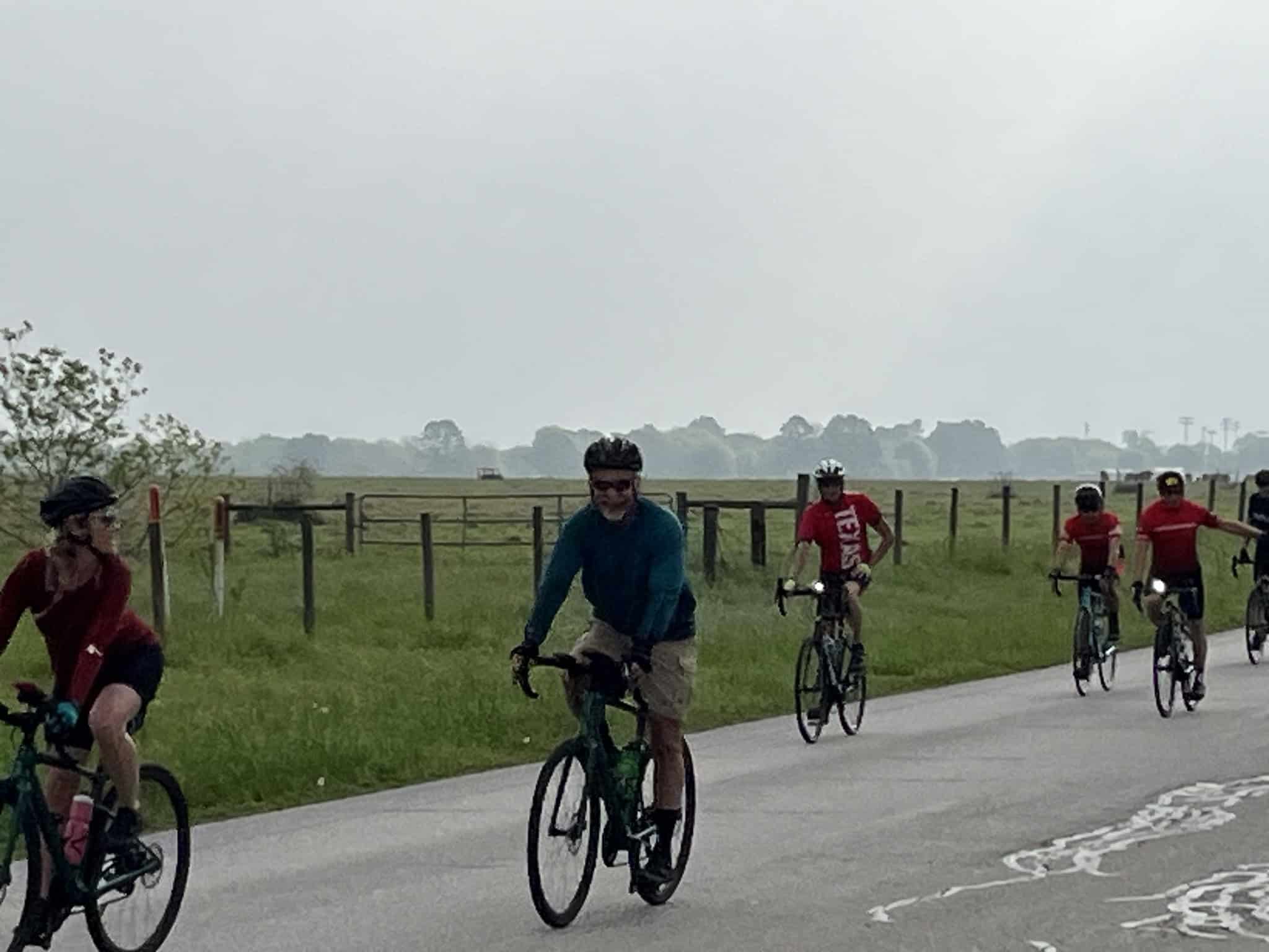Bright blue and red bicycles on a scenic rural bike trail with group riders enjoying outdoor cycling fun.