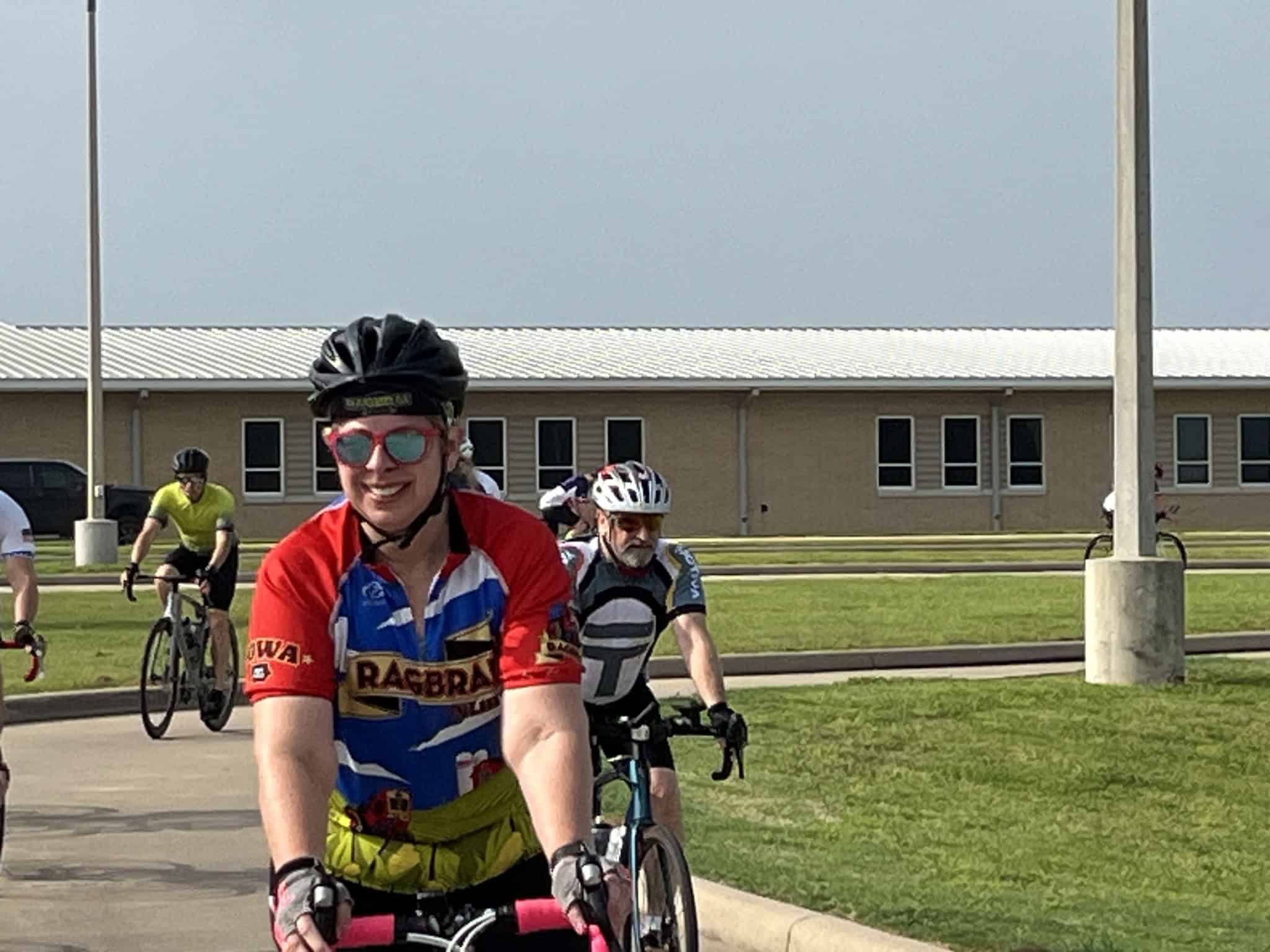 Vibrant cyclist wearing a blue and red jersey and helmet, enjoying a group bike ride outdoors.