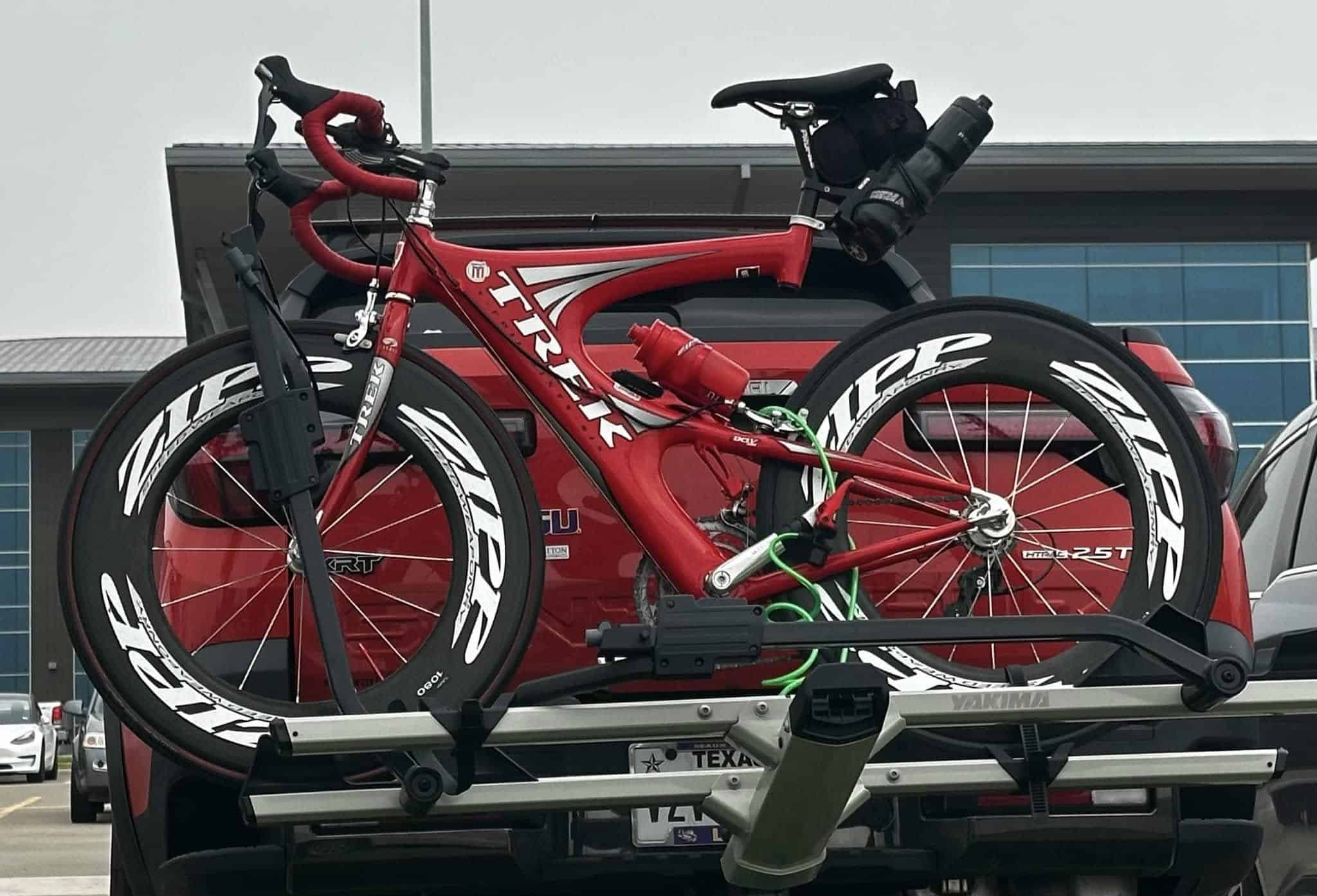 High-performance red bicycle secured on vehicle roof rack for Bluebonnet Express cycling trips.