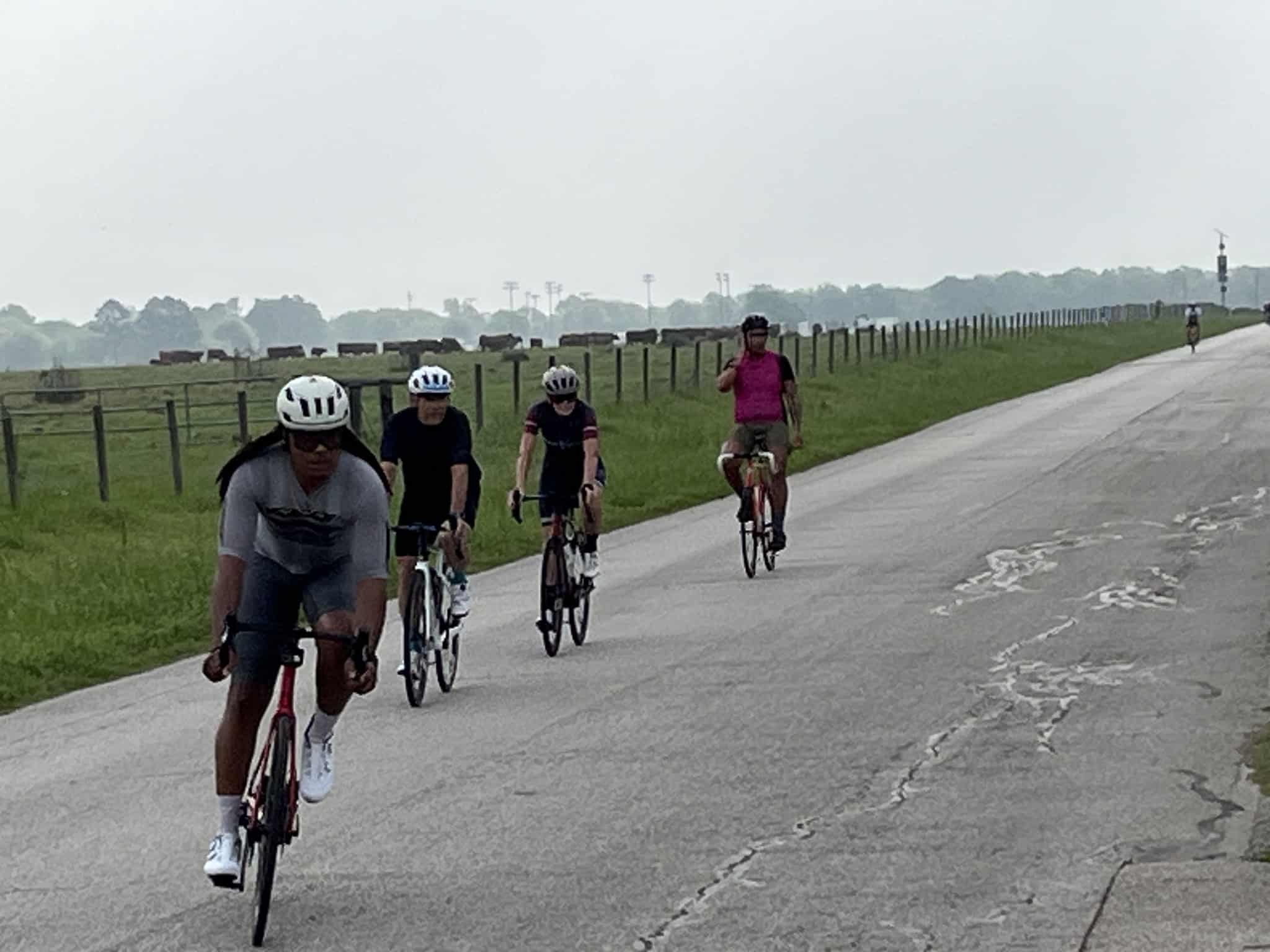 Cyclists riding on a scenic rural road under an overcast sky, part of Bluebonnet Express bike tour.