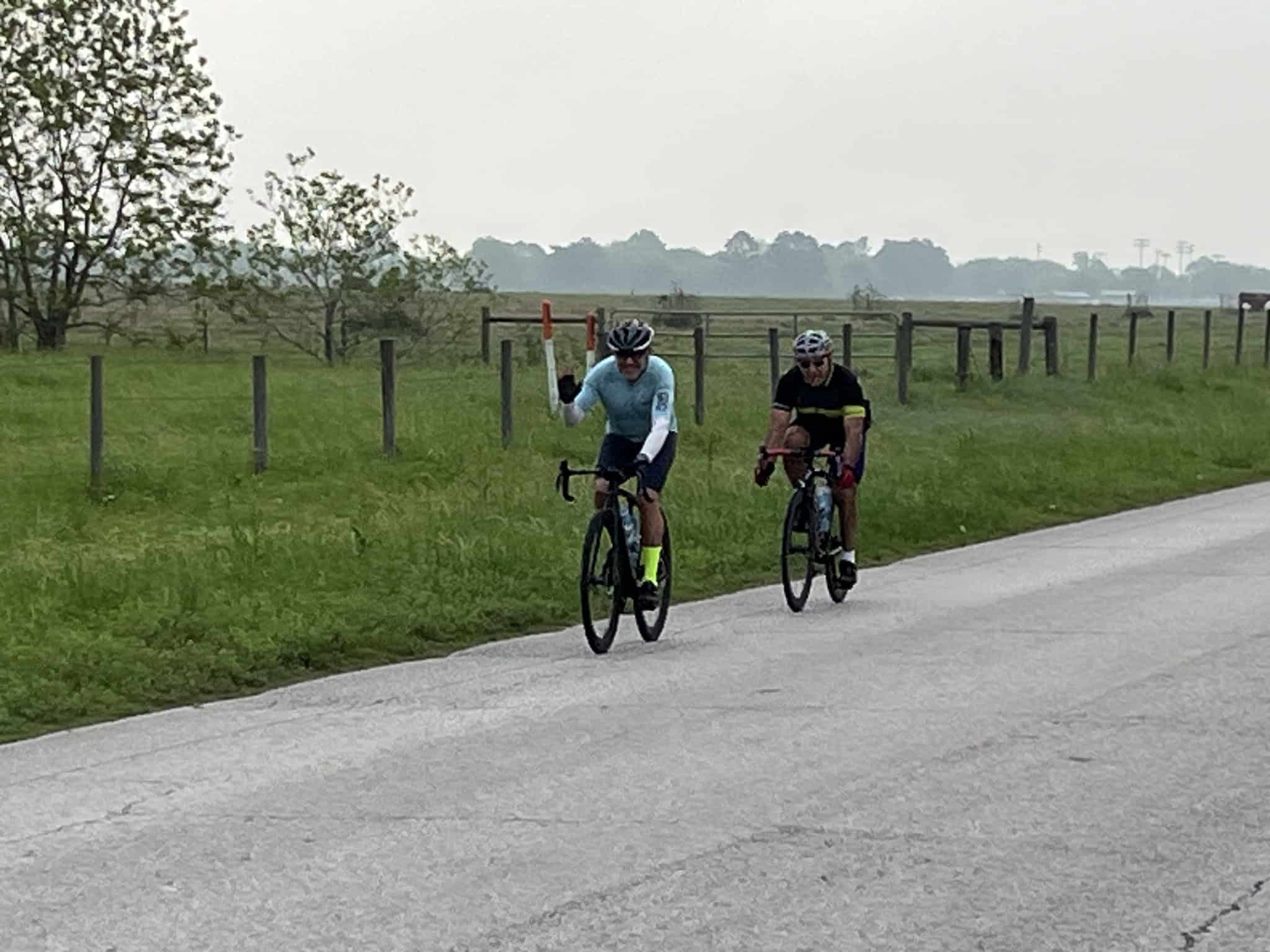 Cyclists on a scenic rural bike route under an overcast sky.