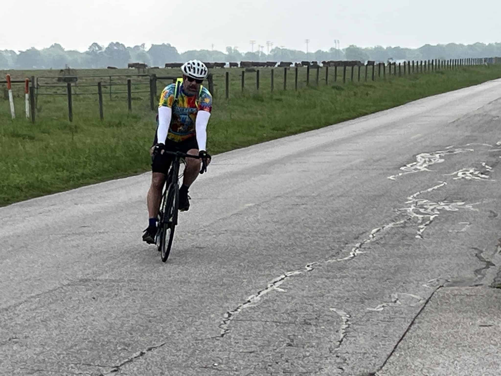 Rider on a scenic countryside bike ride along a cracked rural road in Texas.