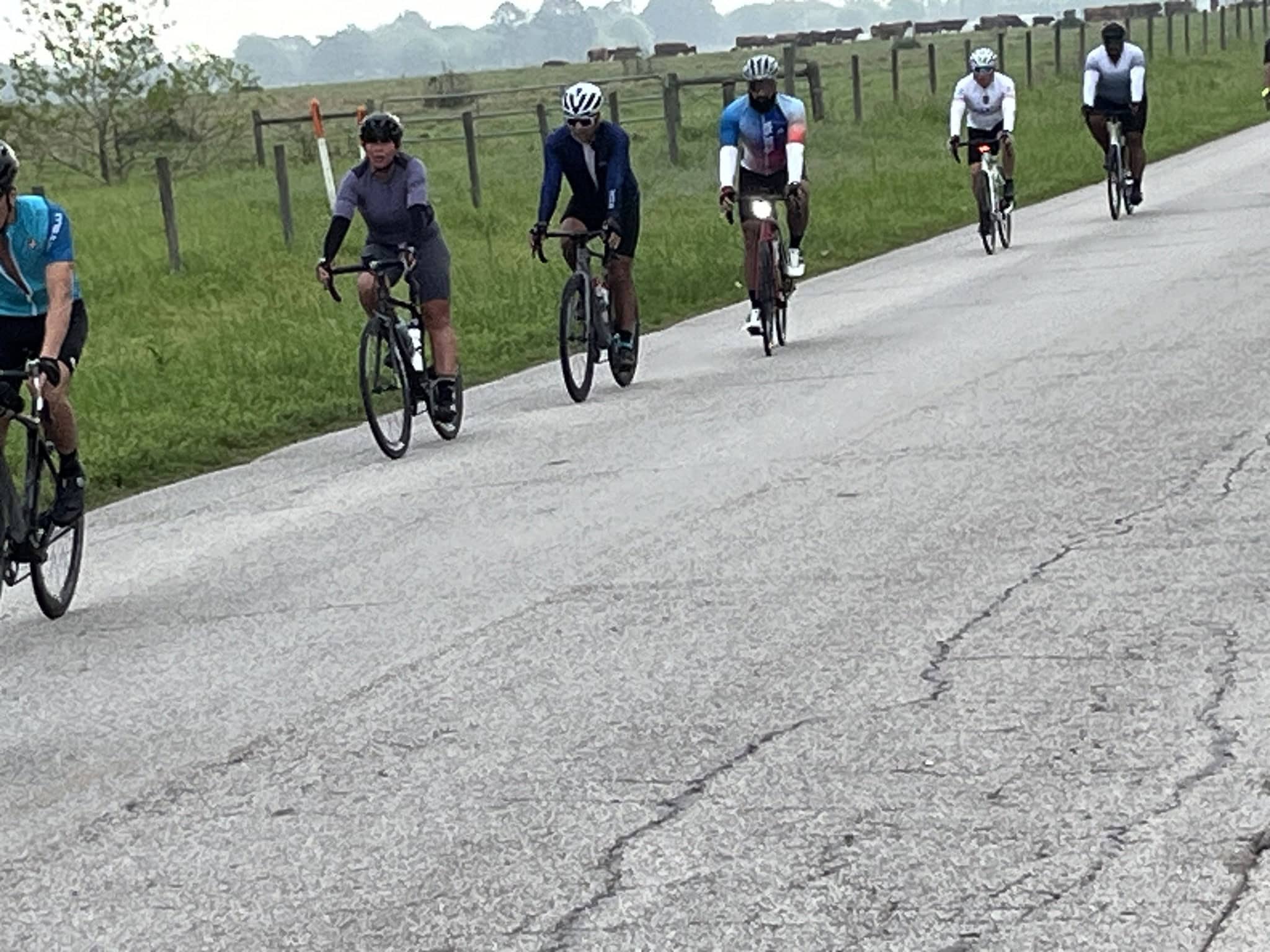 Cyclists riding on a scenic rural road in a group during daytime for outdoor biking.