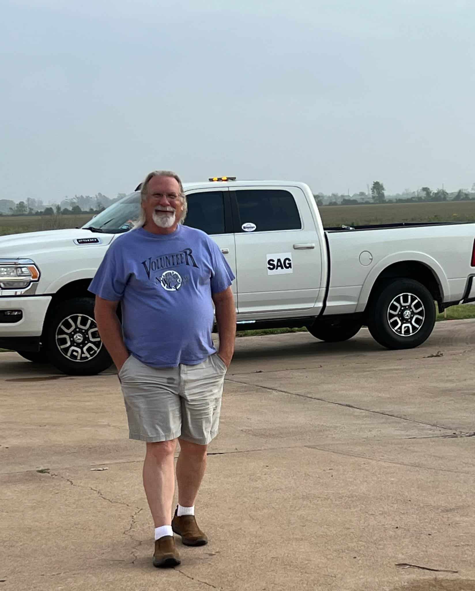 Volunteer bicycle driver standing in front of a white SAG support truck for Bluebonnet Express cycling event.