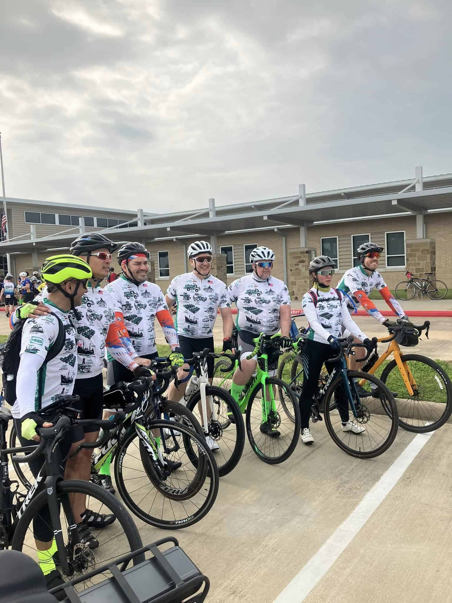 Riders with bicycles ready for a cycling event, wearing matching jerseys, helmets, and gear.