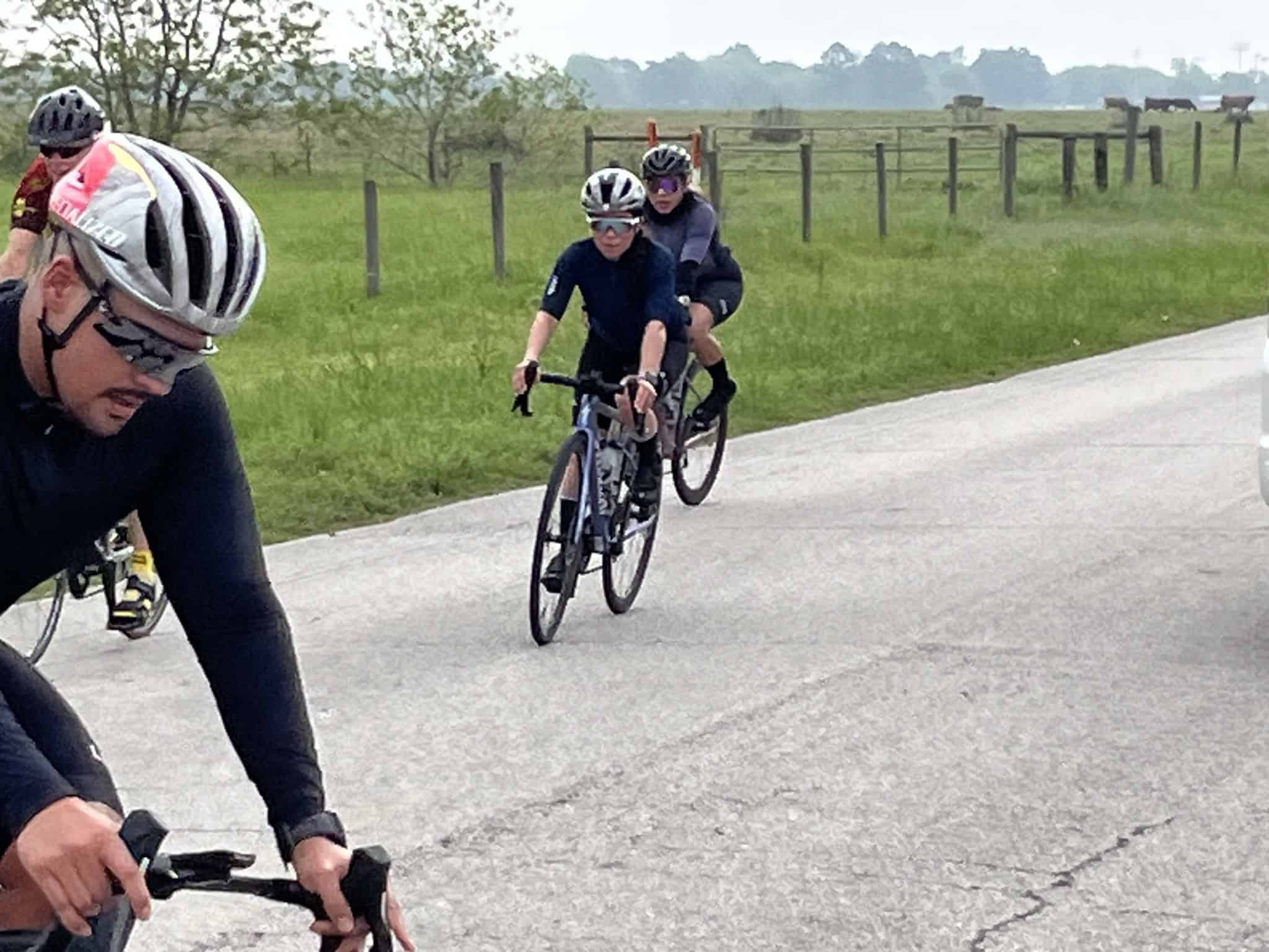 Bike race on rural road with cyclists wearing helmets and sports gear near Bluebonnet fields.