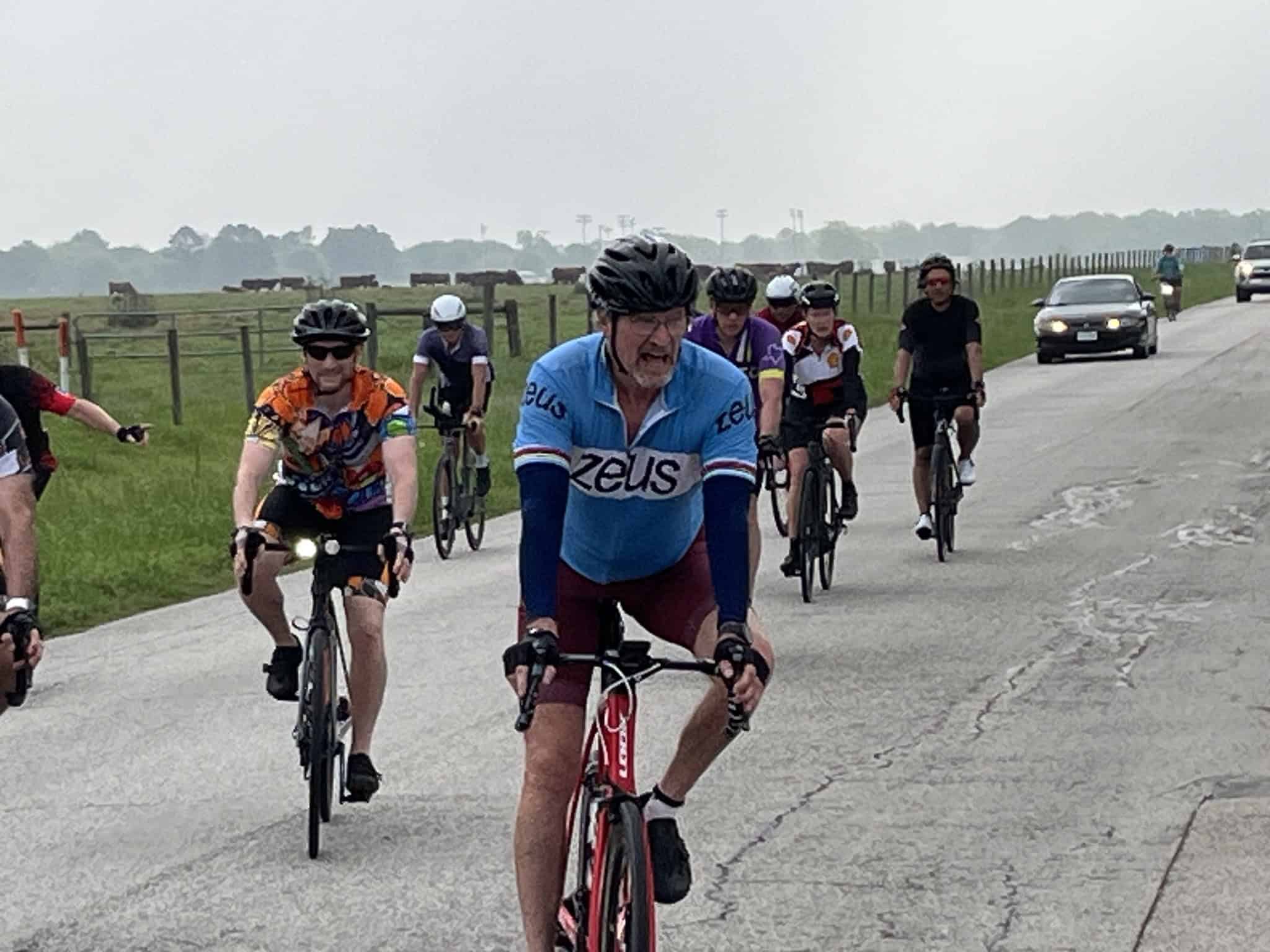 Vibrant cycling group riding on a rural road with scenic background, promoting Bluebonnet Express cycling event.