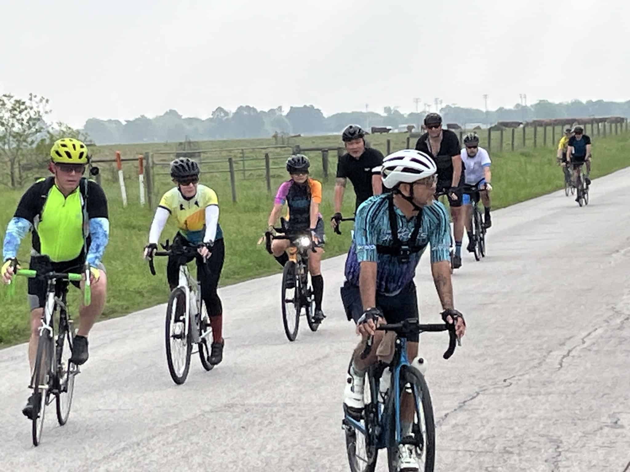 Cyclists enjoying a scenic ride along a rural bike trail with open fields and countryside.