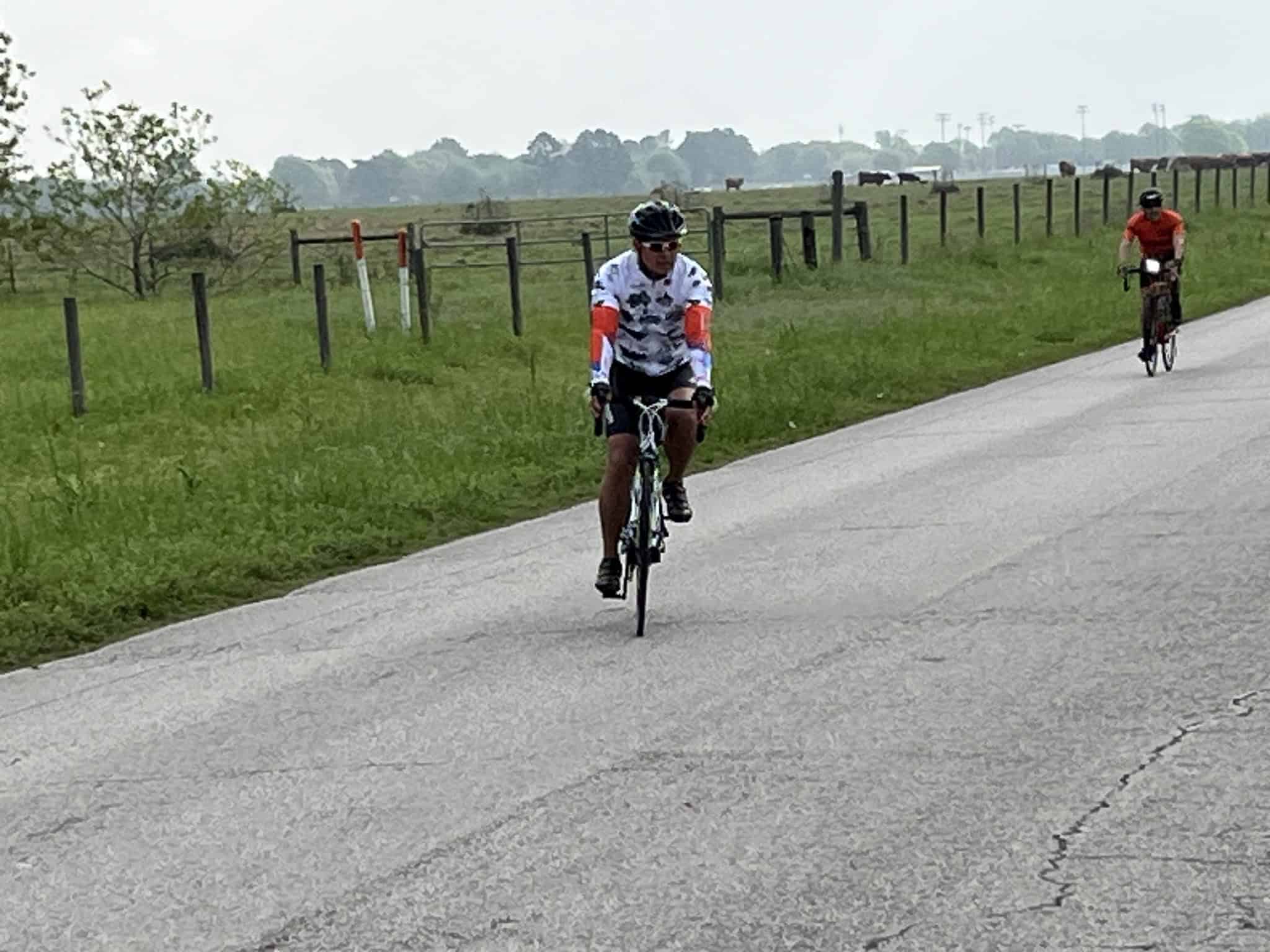 Bright cyclist riding a bike on a rural road during daytime.
