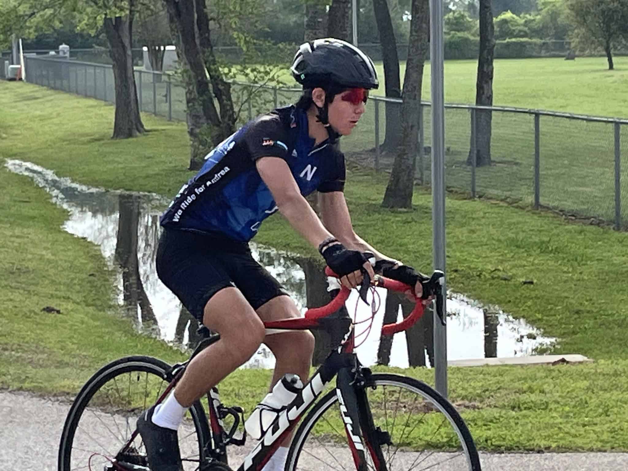 1. Male cyclist riding a red and black bike on a scenic green trail with water reflections.
