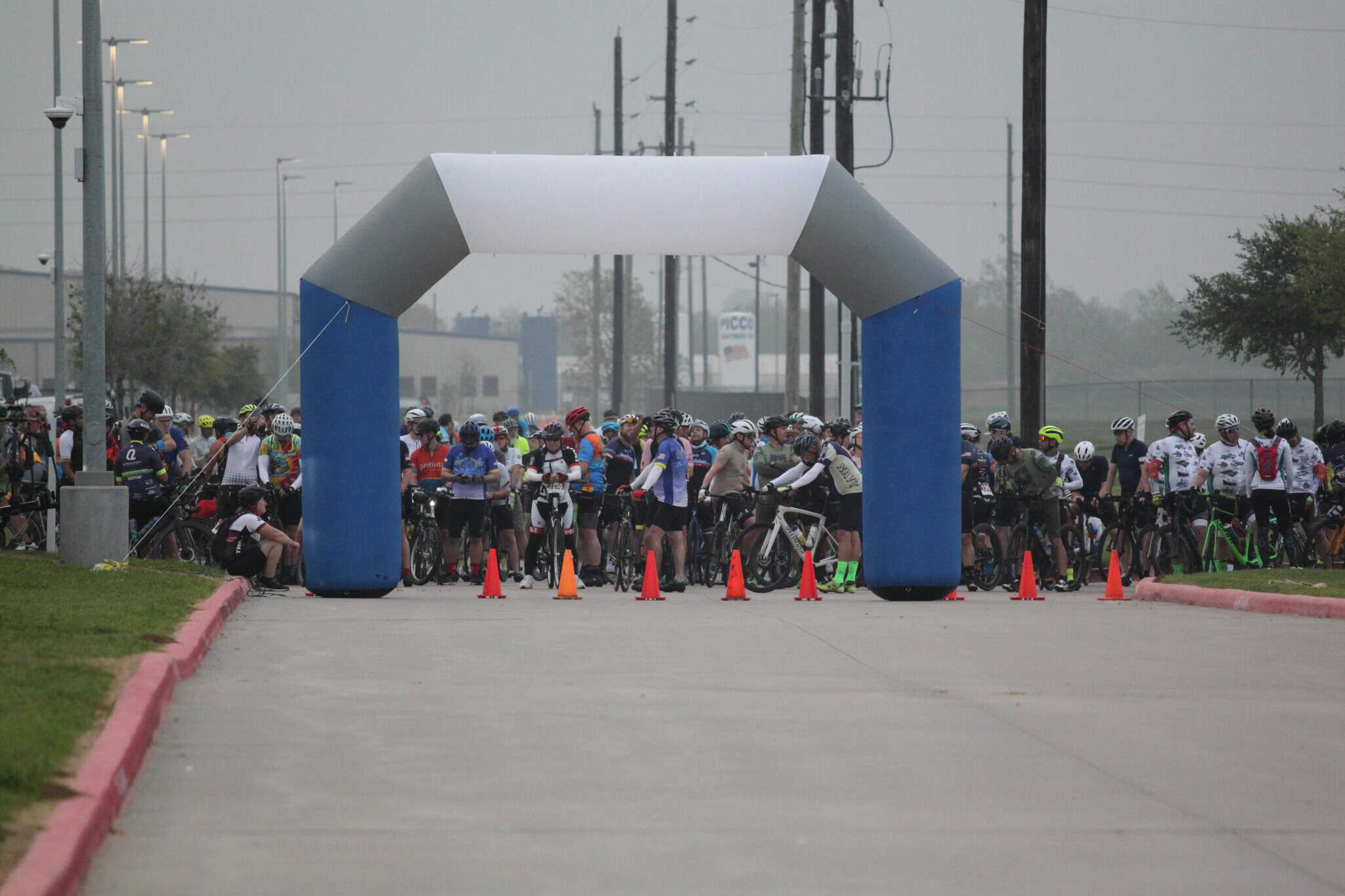Bicycle race start line at Bluebonnet Express event with numerous cyclists and safety cones on a foggy morning.