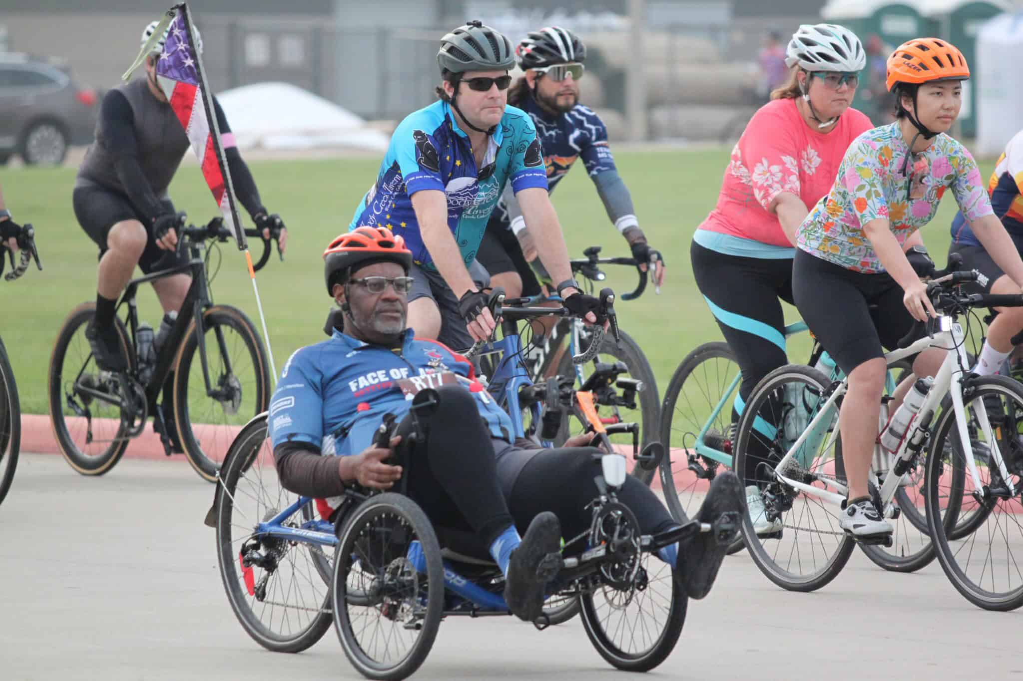 Adult cyclist with a racing wheelchair participating in a group cycling event.