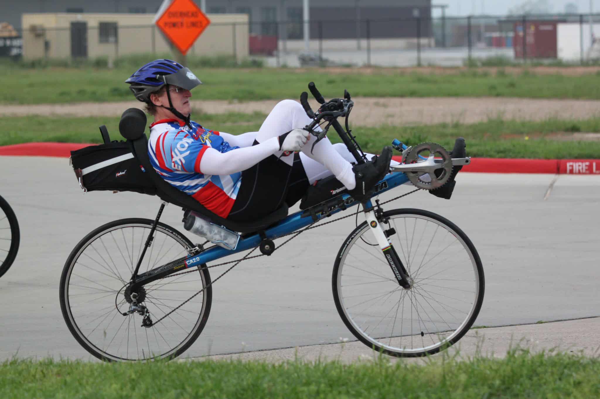 - BMX rider on an adaptive bike with sports gear and helmet in a park setting.