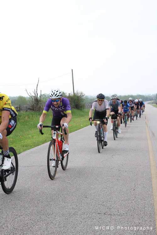 Older adults cycling on rural road during group bike ride.