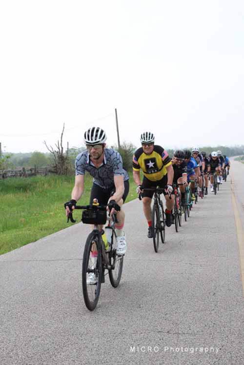 1. Group of cyclists riding on rural road during Bluebonnet Express event.