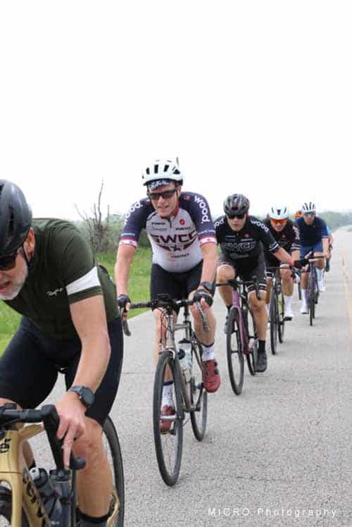 Vibrant group of cyclists riding on scenic rural road during Bluebonnet Express event in Texas.