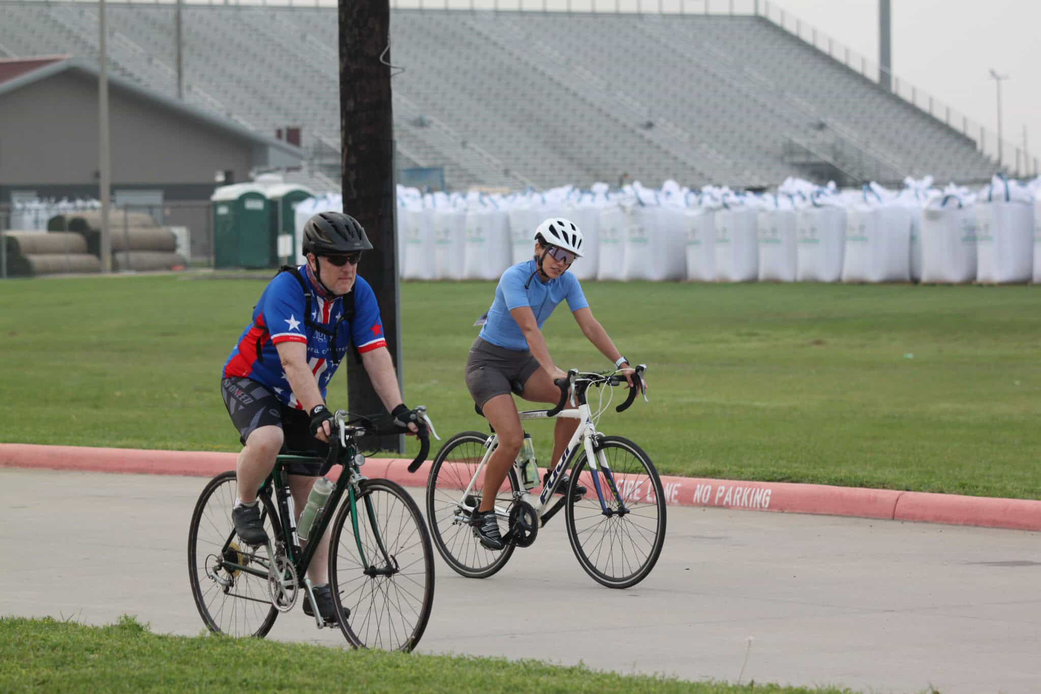 Cyclists riding bikes outdoors on a track, promoting Bluebonnet Express bike services and cycling events.