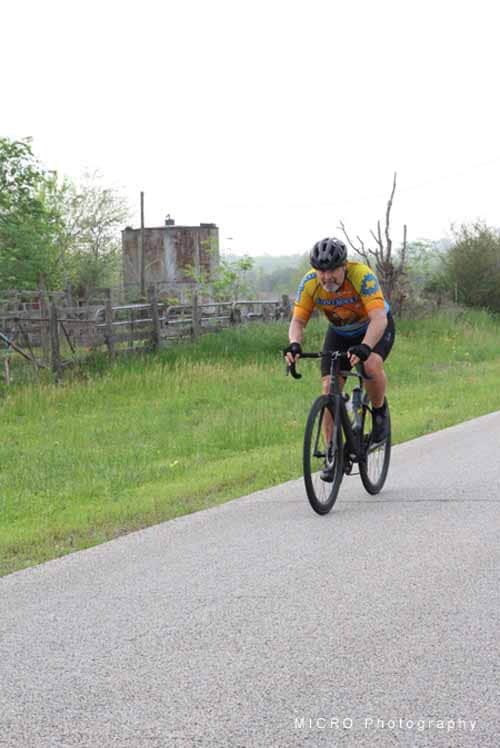 Cyclist riding on rural road during daytime, emphasizing Bluebonnet Express bike event.