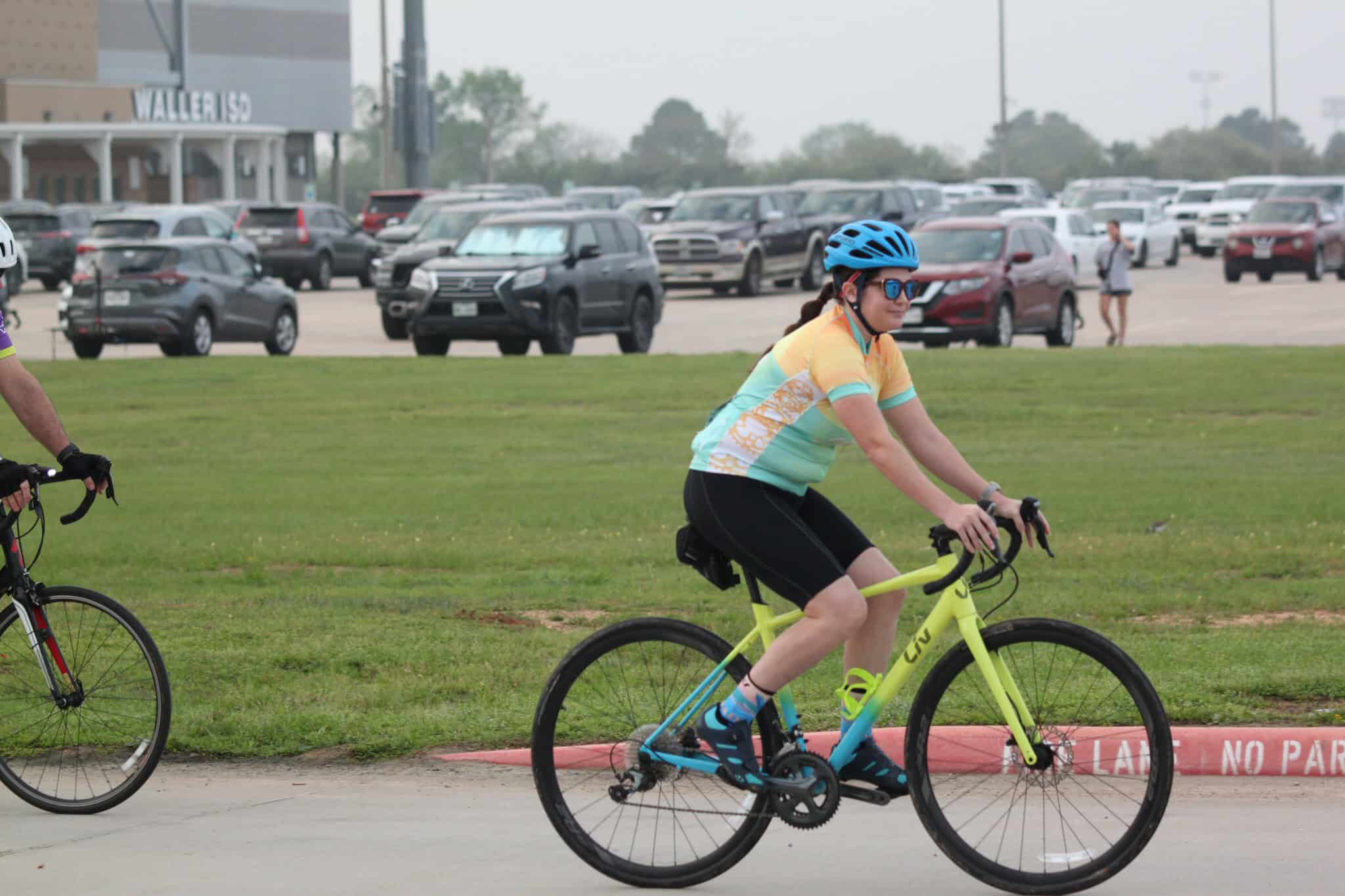 Colorful cyclist riding a bike on the road in a parking lot.