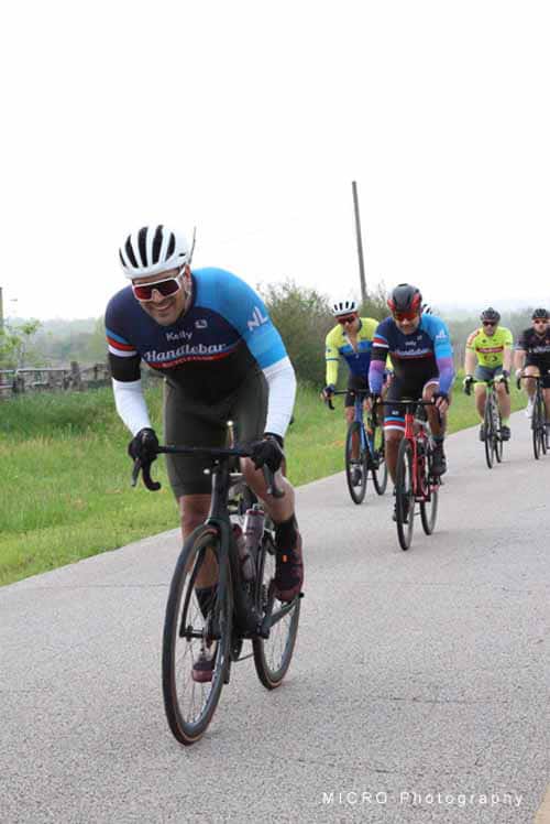 High-performance cyclists riding on rural road during Bluebonnet Express event.