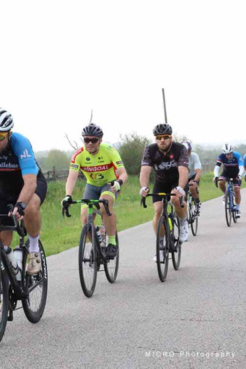Vibrant cyclists riding in the Bluebonnet Express cycling event on a scenic open road.