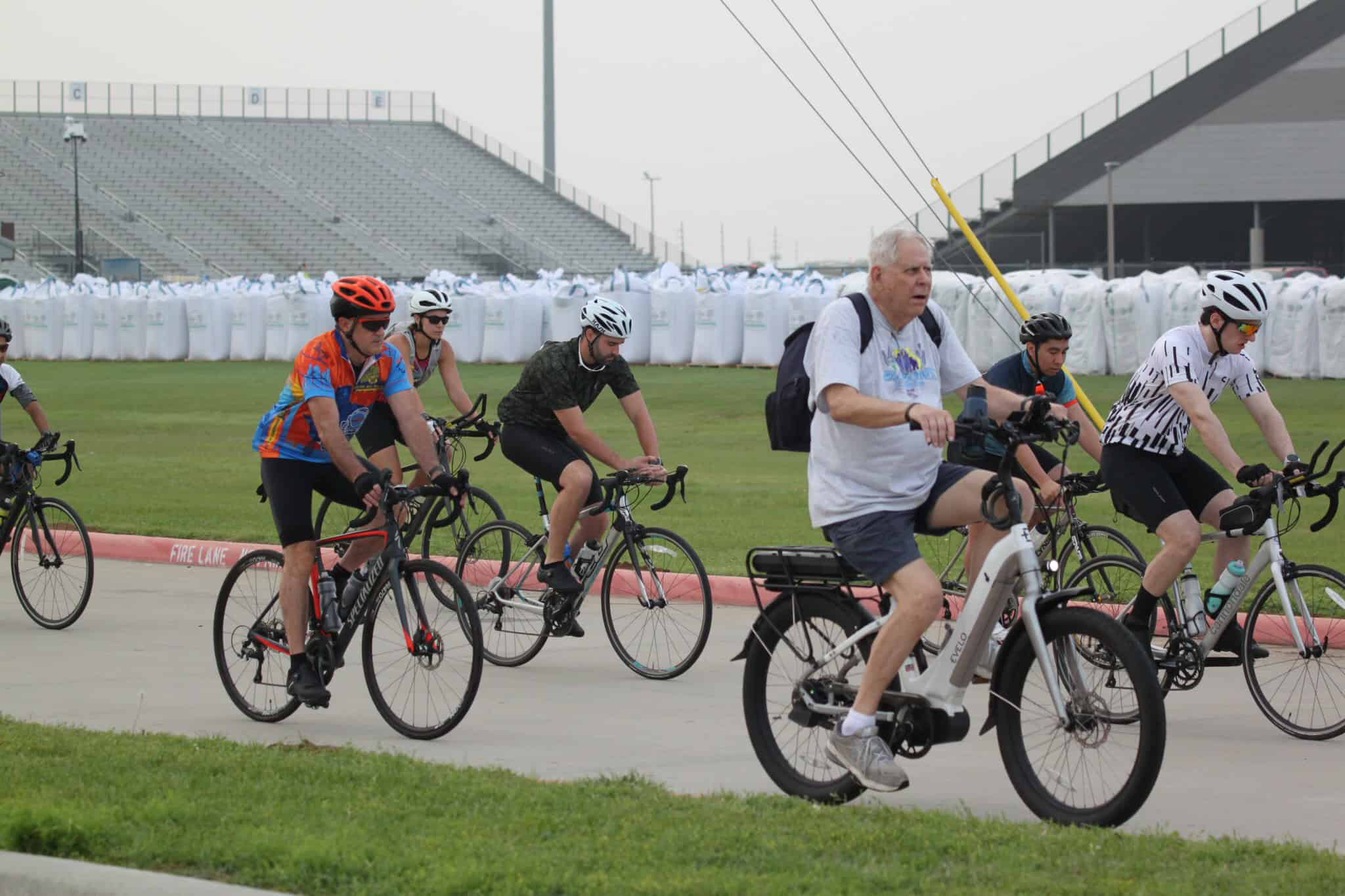 Cyclists riding on a track at Bluebonnet Express event, outdoor biking race on a cloudy day.