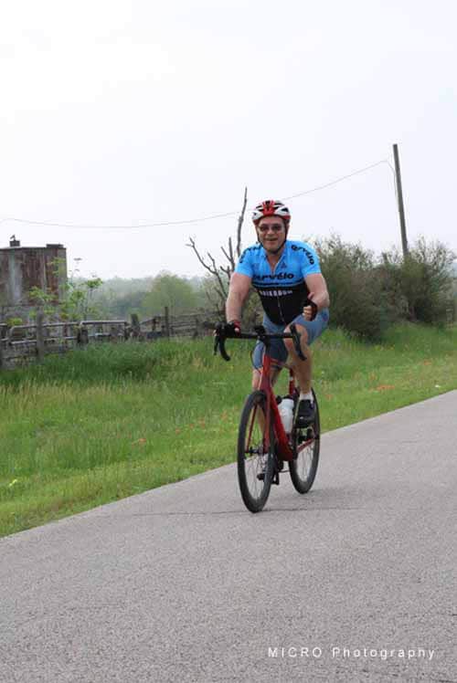 Vast outdoor scenery with cyclist on rural road during daytime.