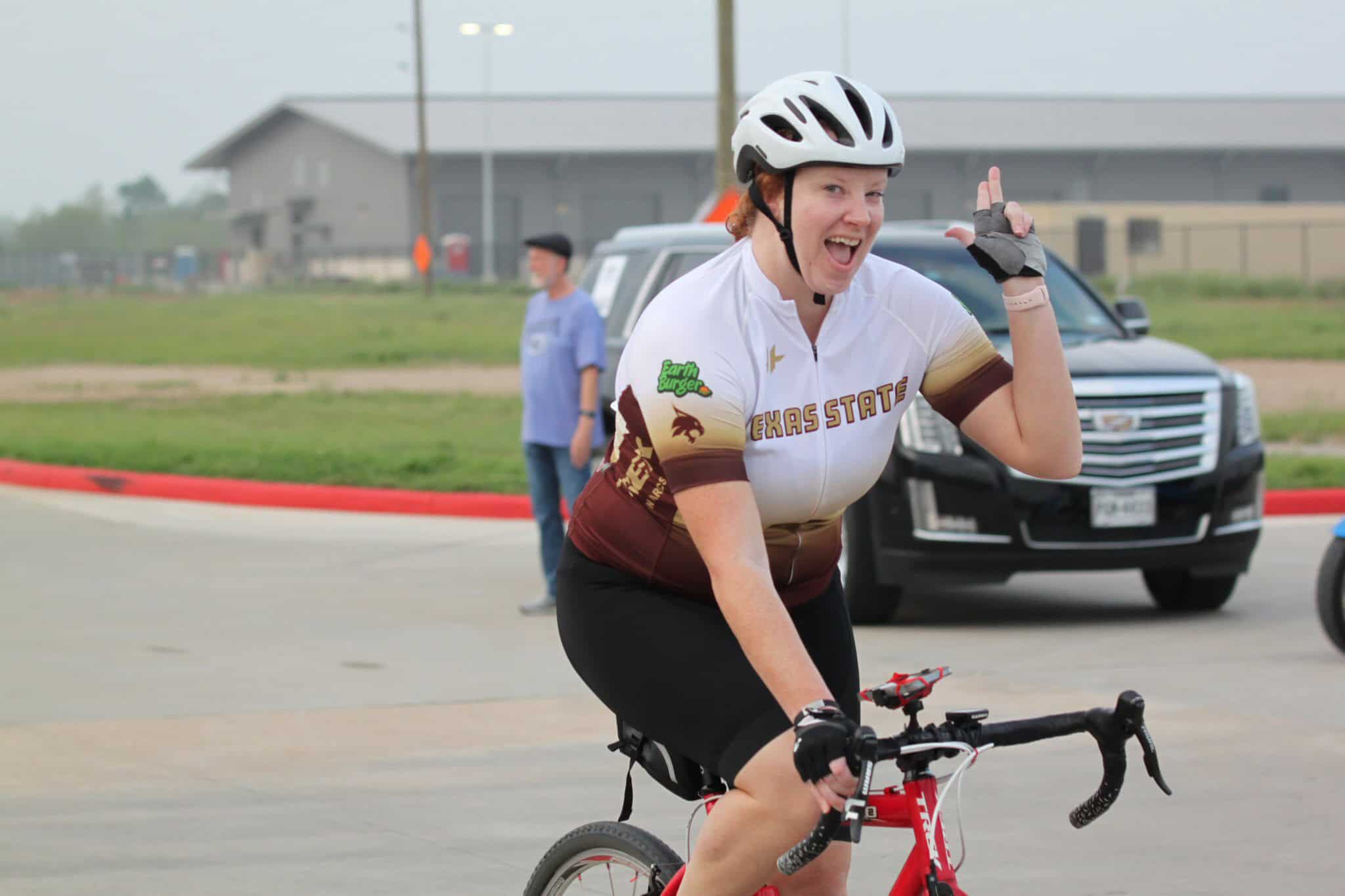 Bright smiling cyclist in Texas State cycling jersey, enjoying riding at Bluebonnet Express event.