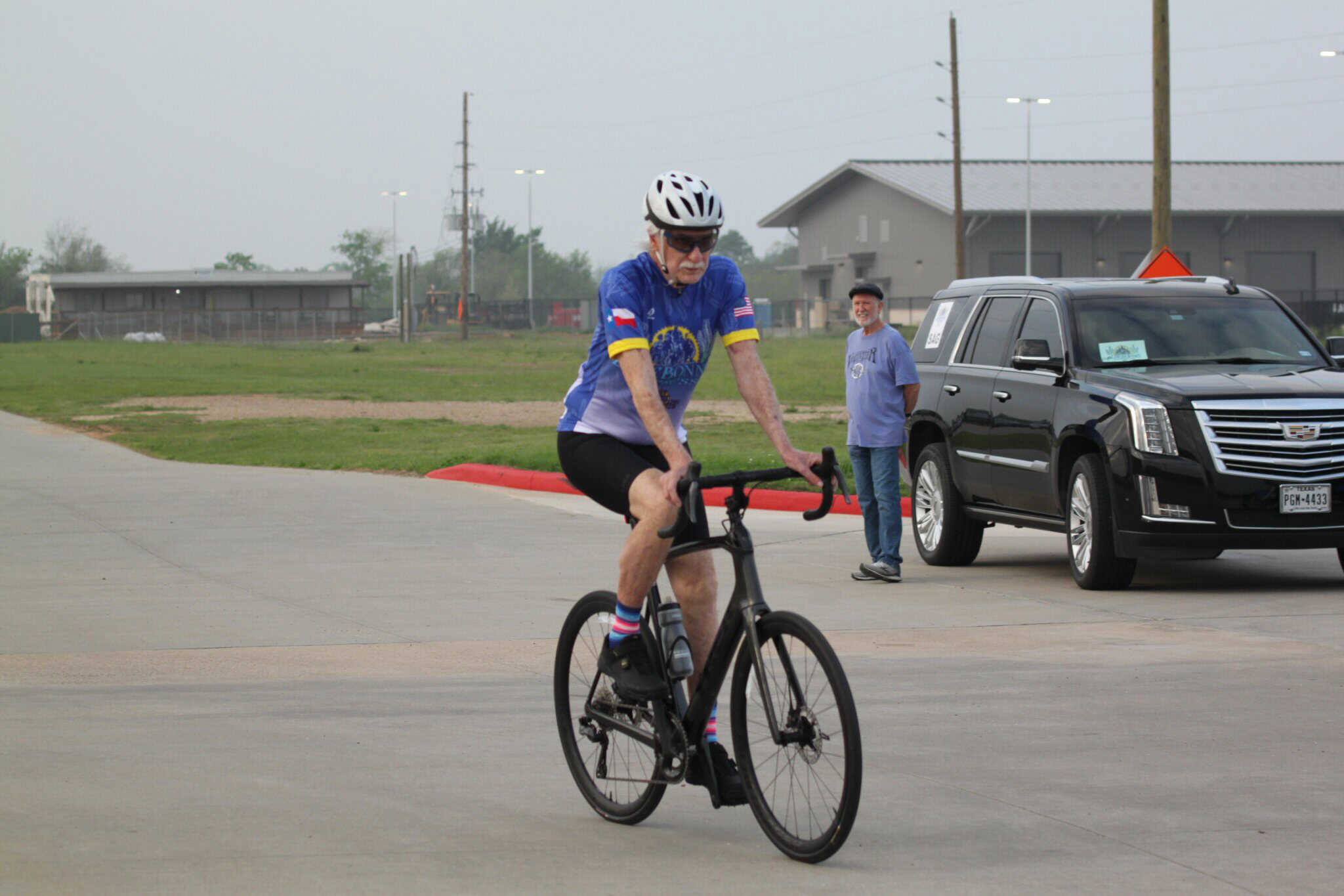 Professional cyclist riding a bike outdoors at Bluebonnet Express event, wearing a blue jersey and helmet.