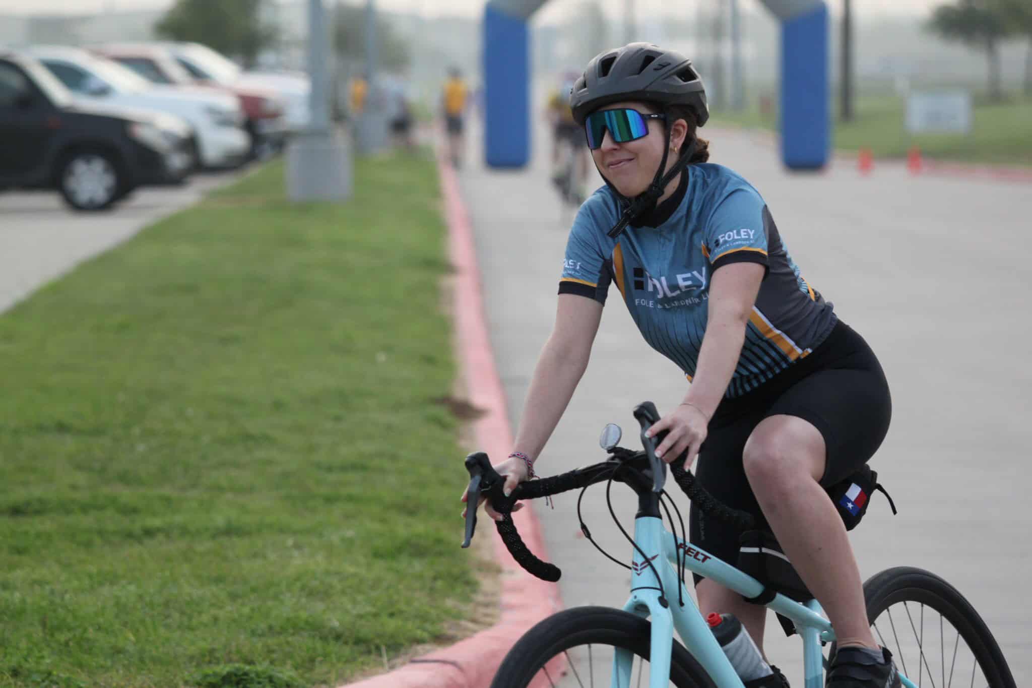 Bright female cyclist with Bluebonnet Express jersey riding bike outdoors during event.