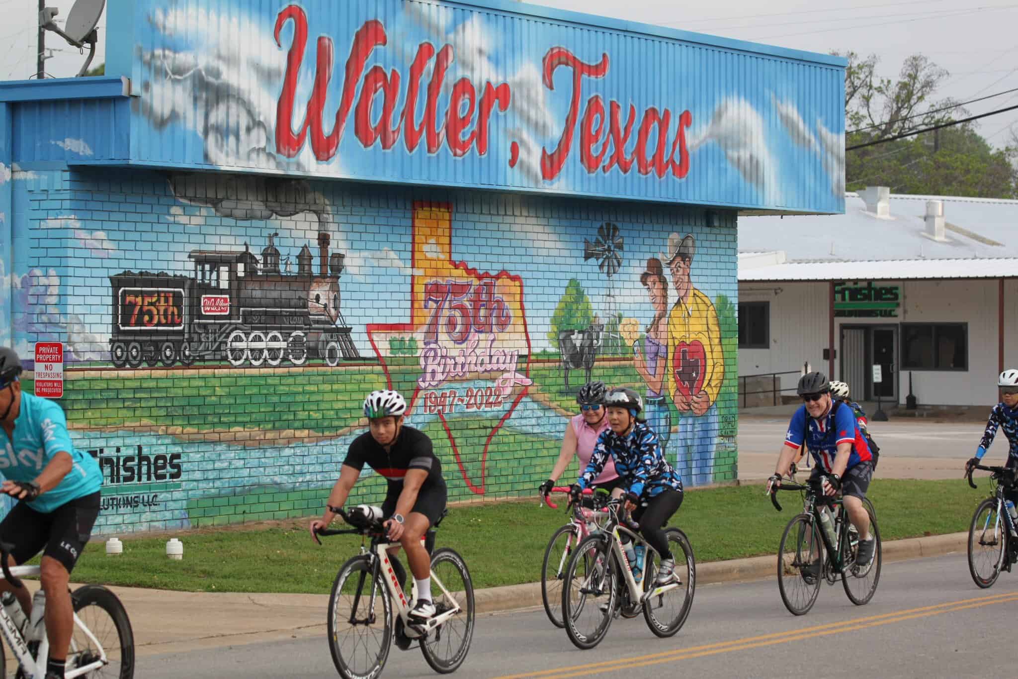 Colorful mural celebrating Waller, Texas 75th anniversary with cyclists riding past.