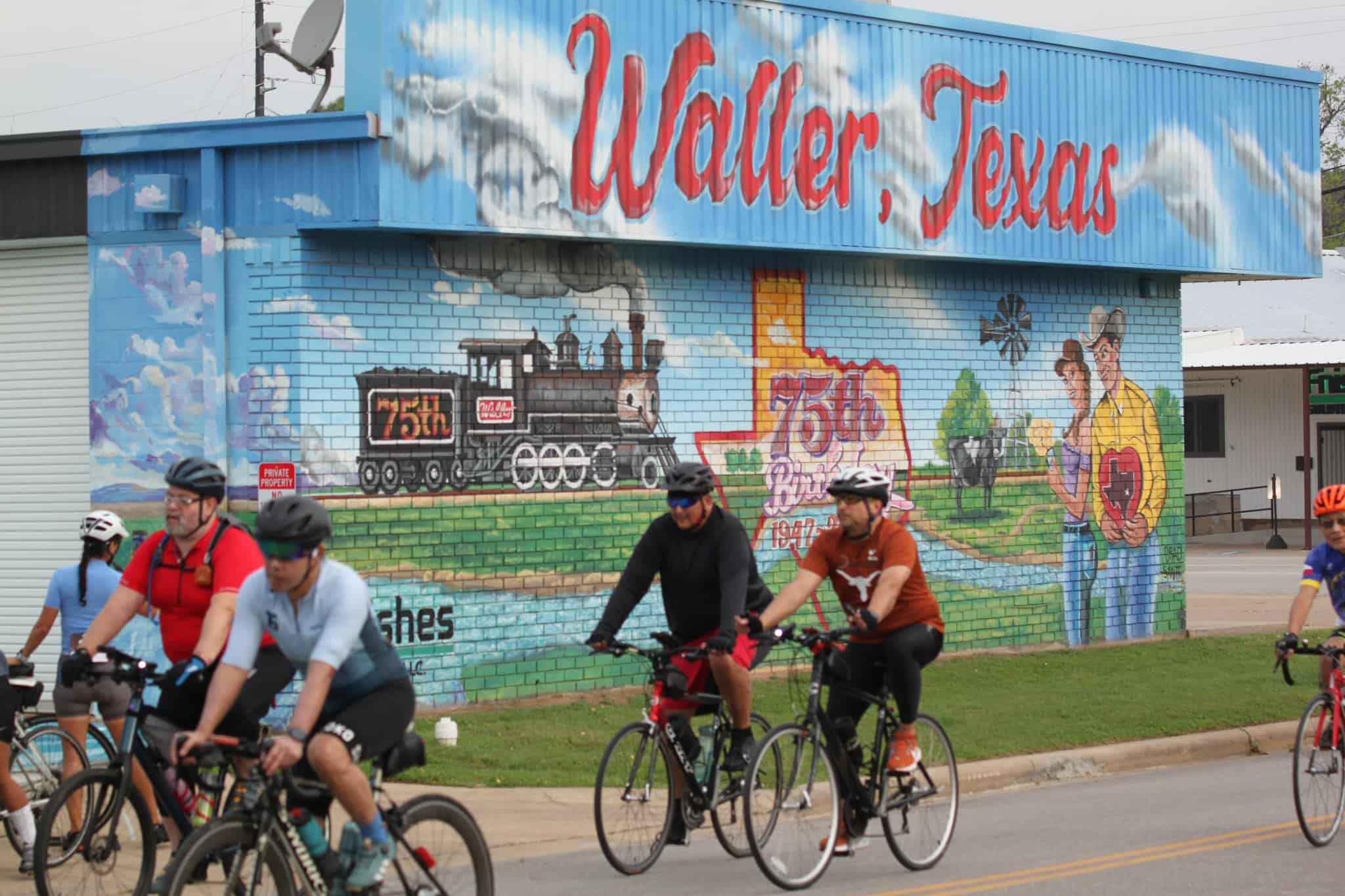 Colorful mural of Waller, Texas celebrating 75th anniversary with train and couple on wall.