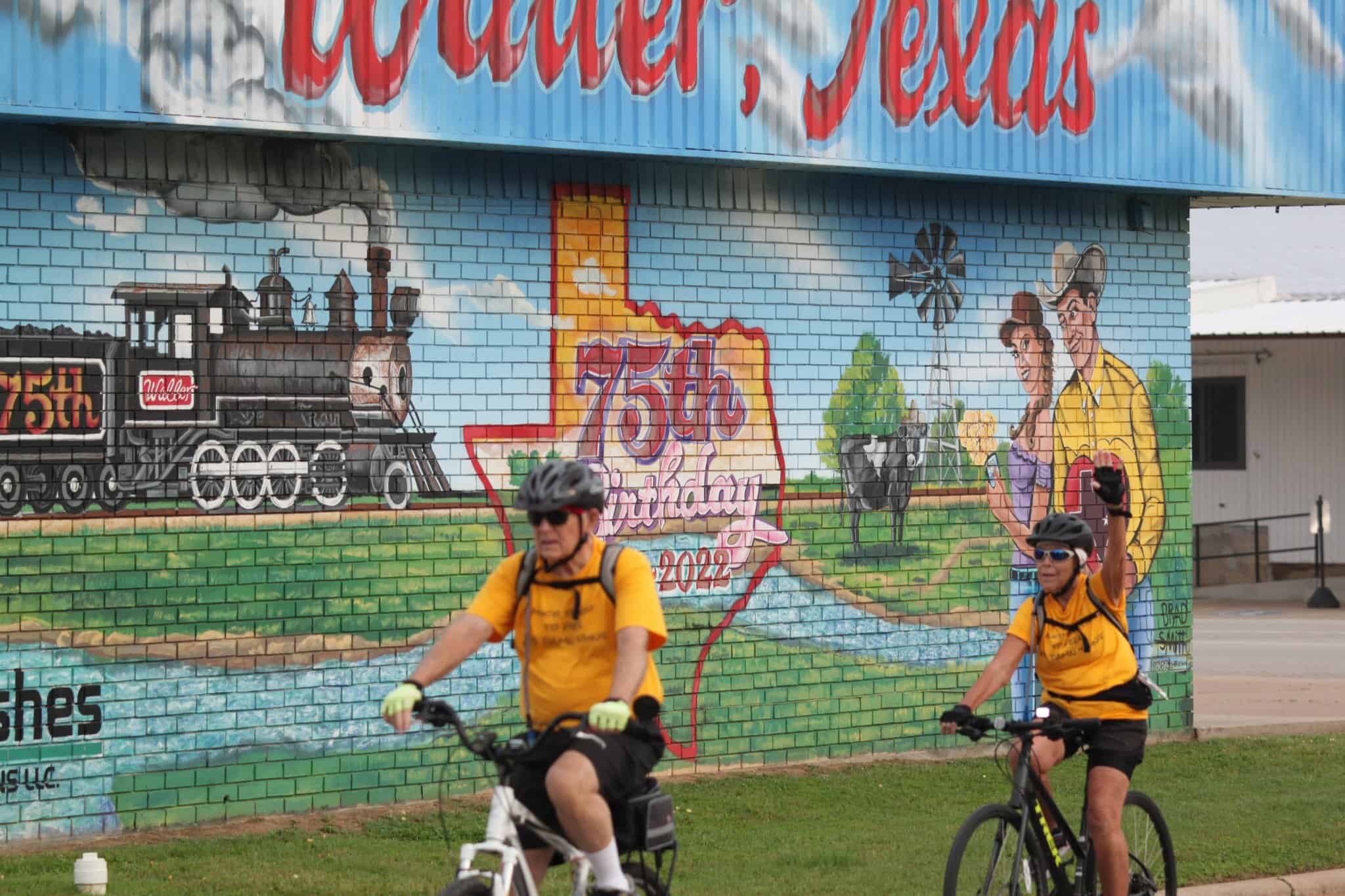 Brightly painted mural celebrating 75th birthday of historic Texas town, featuring trains and local scenery.