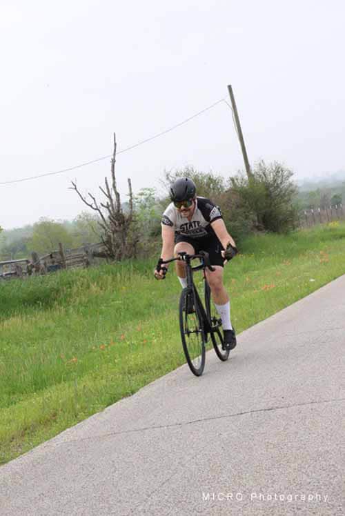 High-performance cyclist riding on scenic rural road during training session.