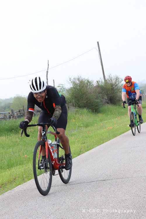 High-speed biking on rural road, cyclists wearing helmets and sporty gear.