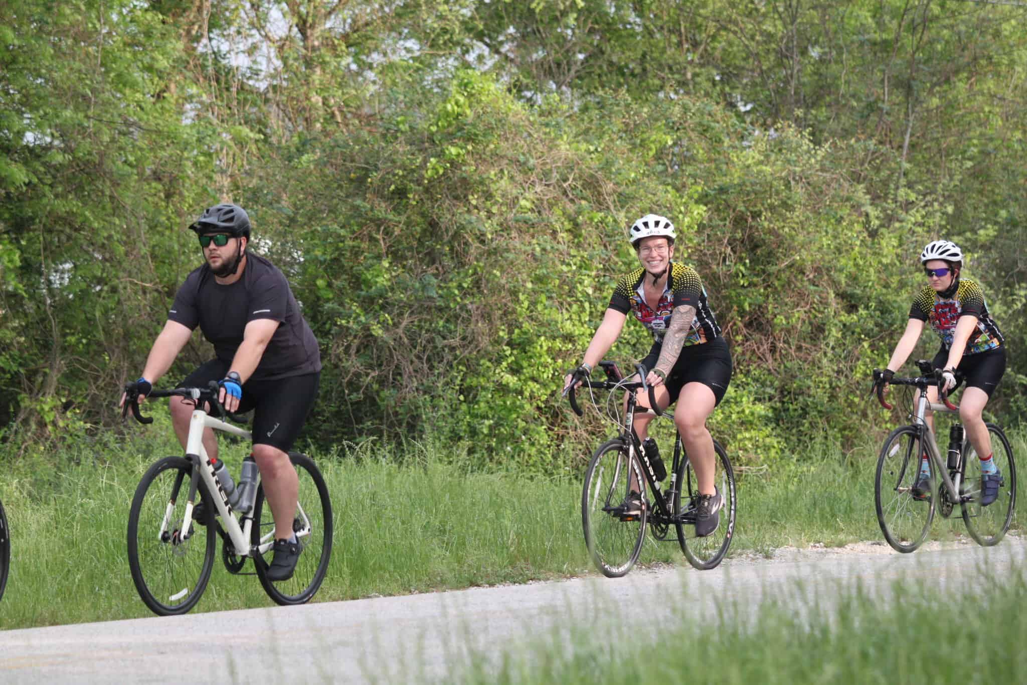 Cyclists riding on a scenic trail in nature with helmets and sportswear for outdoor biking.