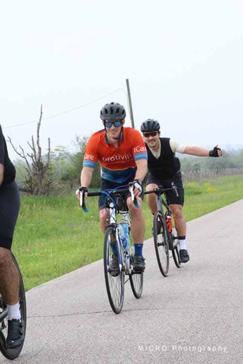 Velo cyclists riding on a rural road, enjoying a group bike tour with Bluebonnet Express.