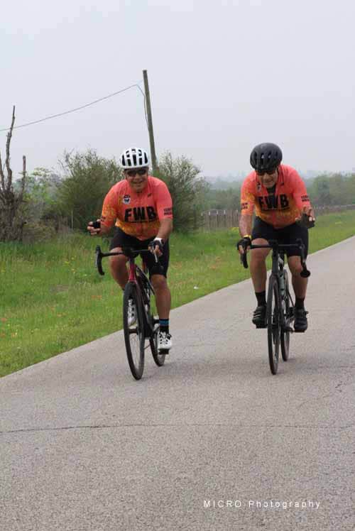 Active cyclists riding on scenic rural road in Bluebonnet Express event.